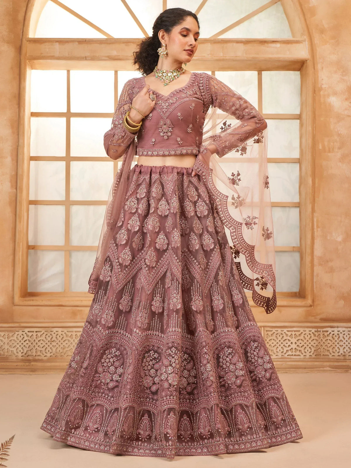 Elegant mauve designer lehenga choli with intricate embroidery and sheer dupatta, perfect for Indian weddings and festive occasions.