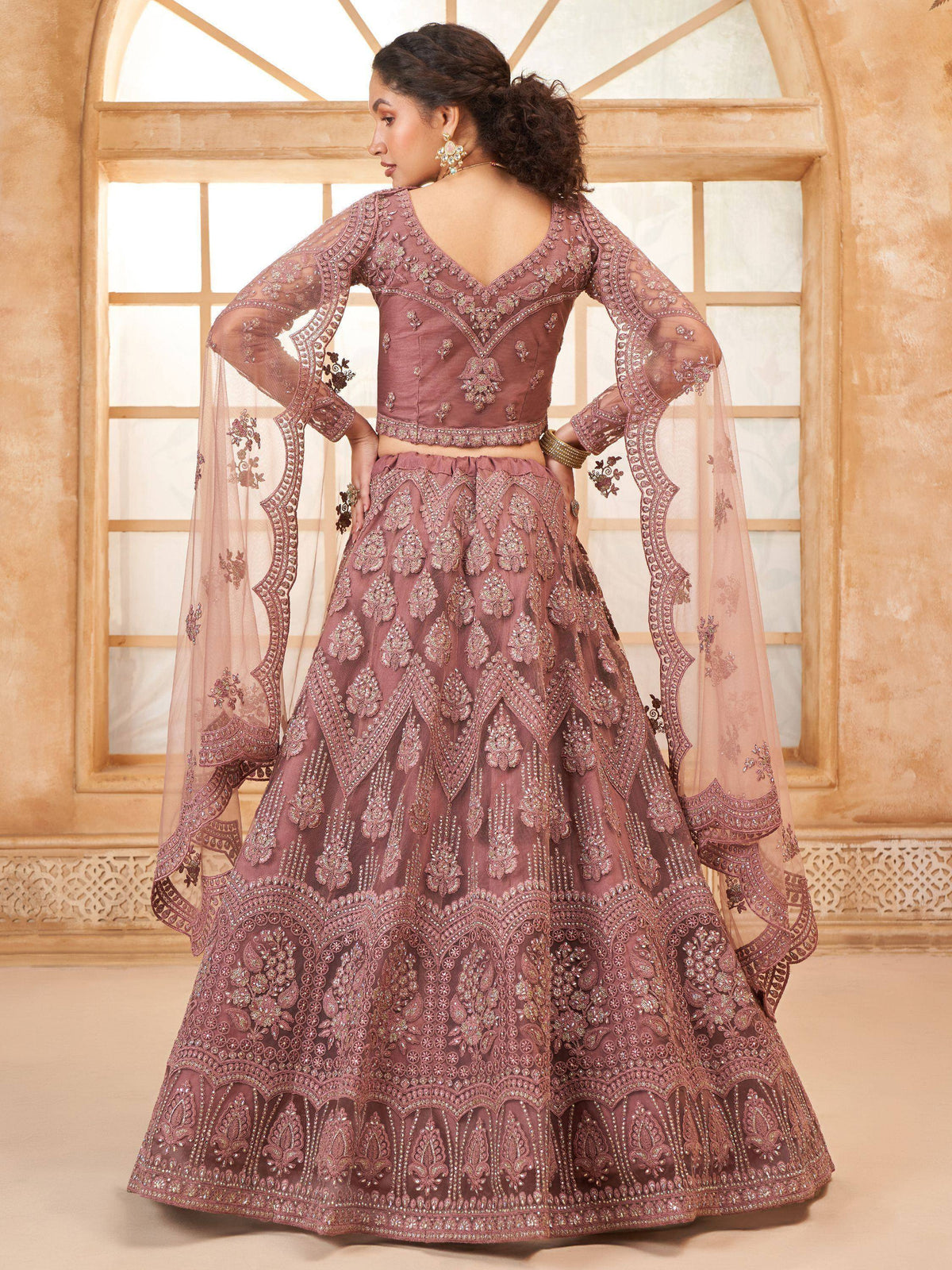 Elegant mauve lehenga choli with intricate embroidery and sheer bell sleeves, perfect for Indian weddings or festive occasions.