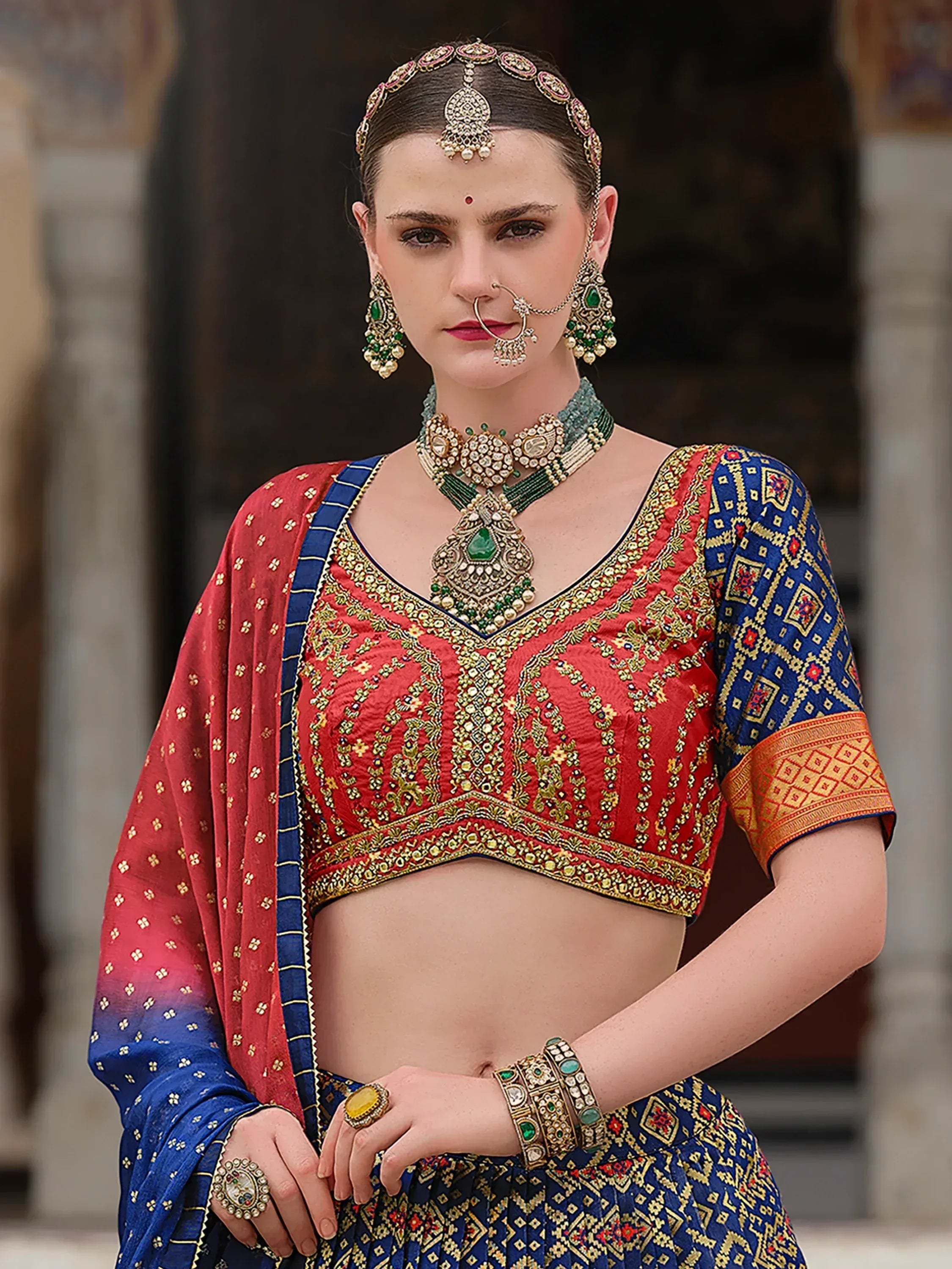 Red and blue embroidered lehenga choli with traditional Indian jewelry for festive occasions