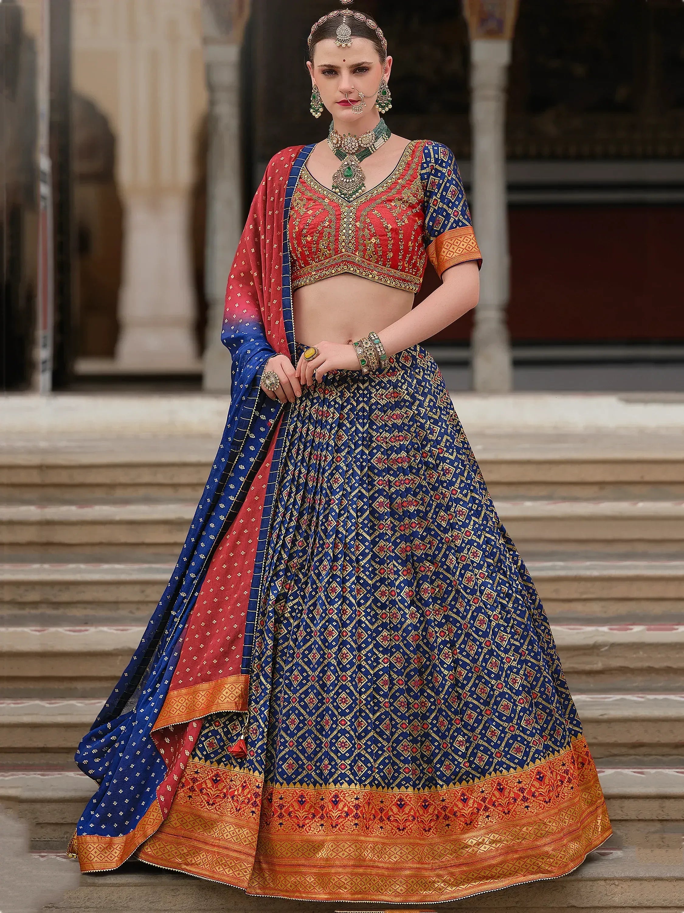 Blue and red designer lehenga choli with intricate gold embroidery, perfect for Indian weddings and festive occasions.