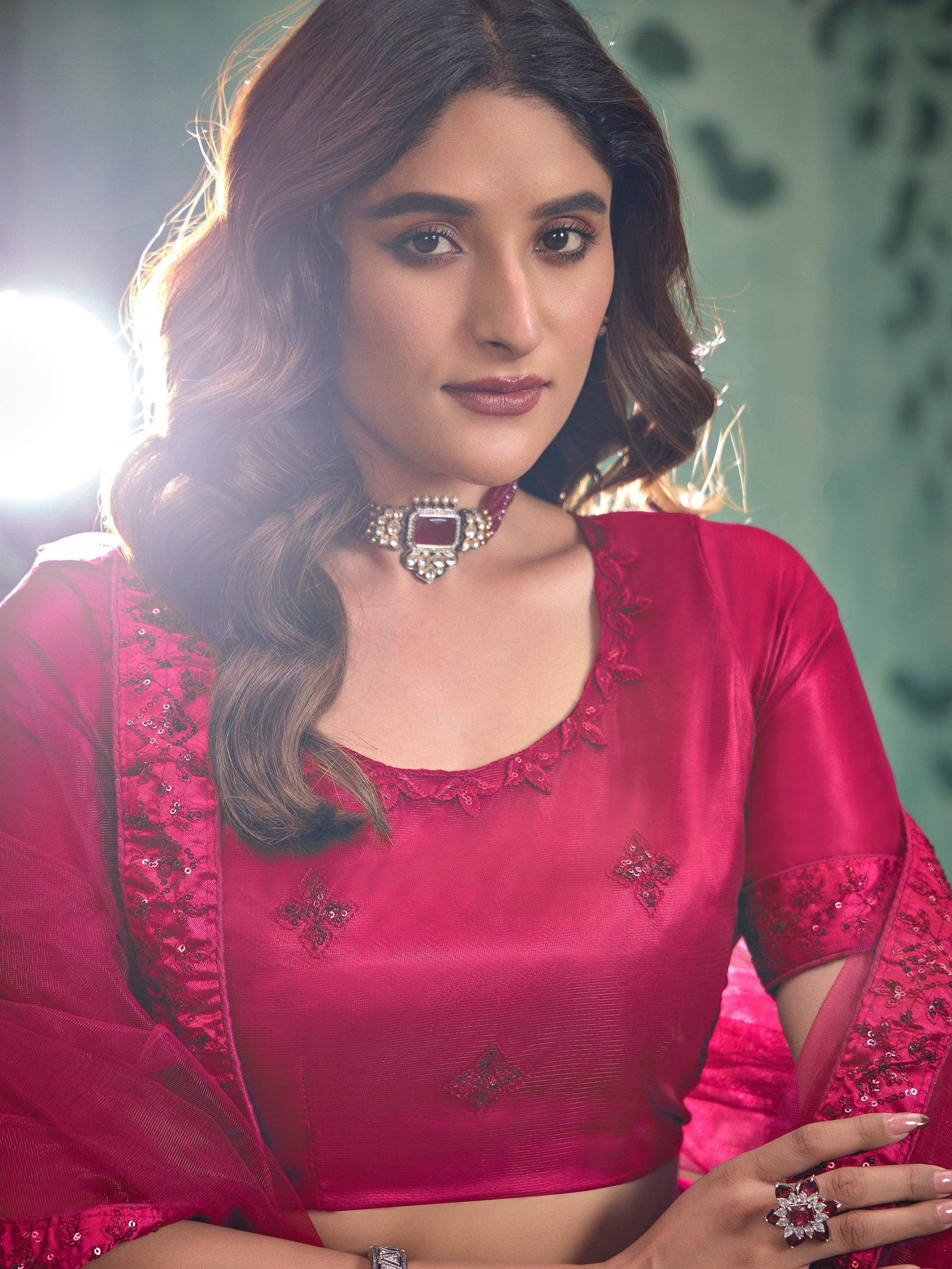 Woman in vibrant pink ethnic blouse with sequin embroidery and statement jewelry