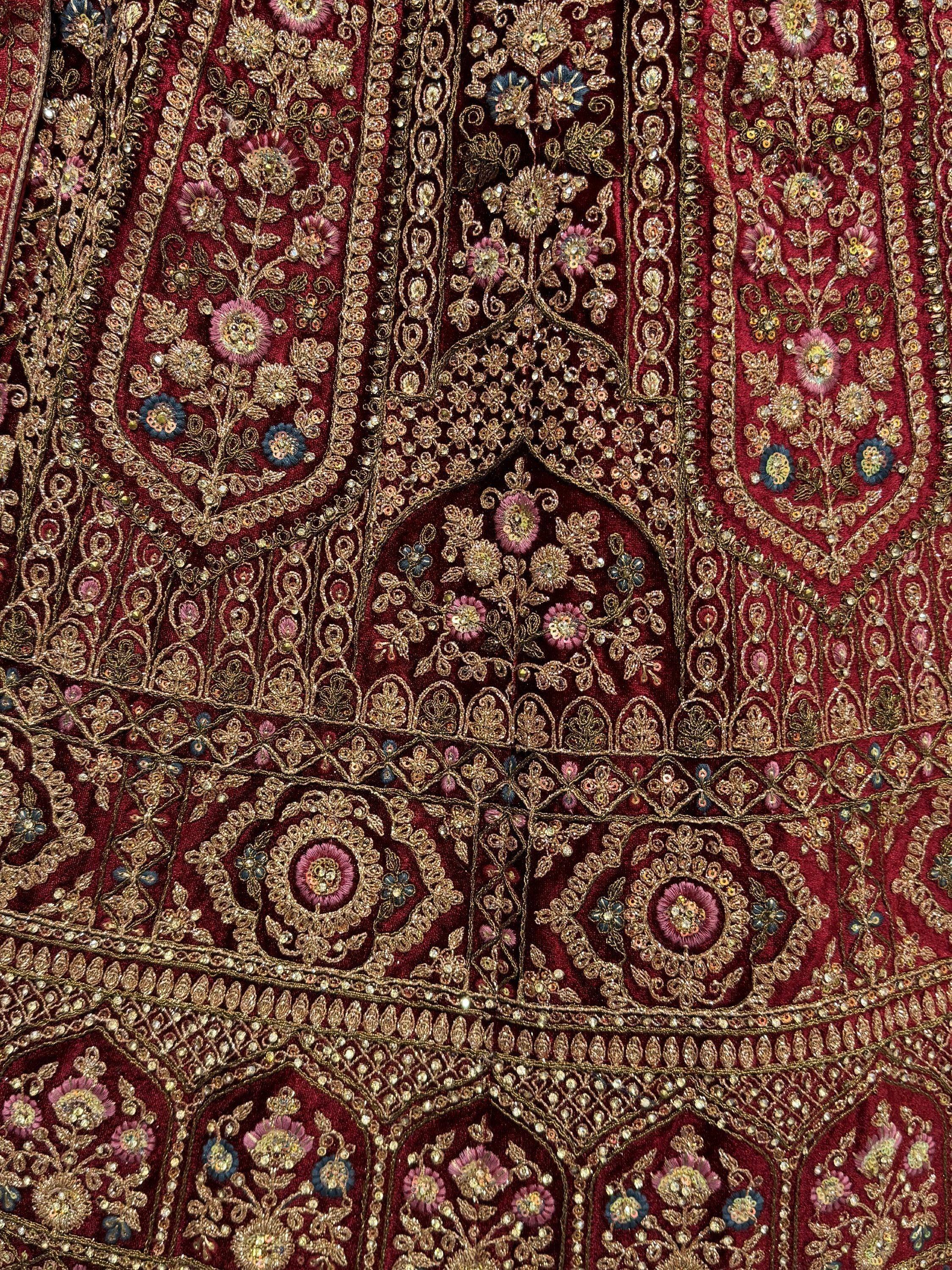 Rich maroon ethnic wear with intricate gold embroidery, floral motifs, and sequin detailing for festive occasions.