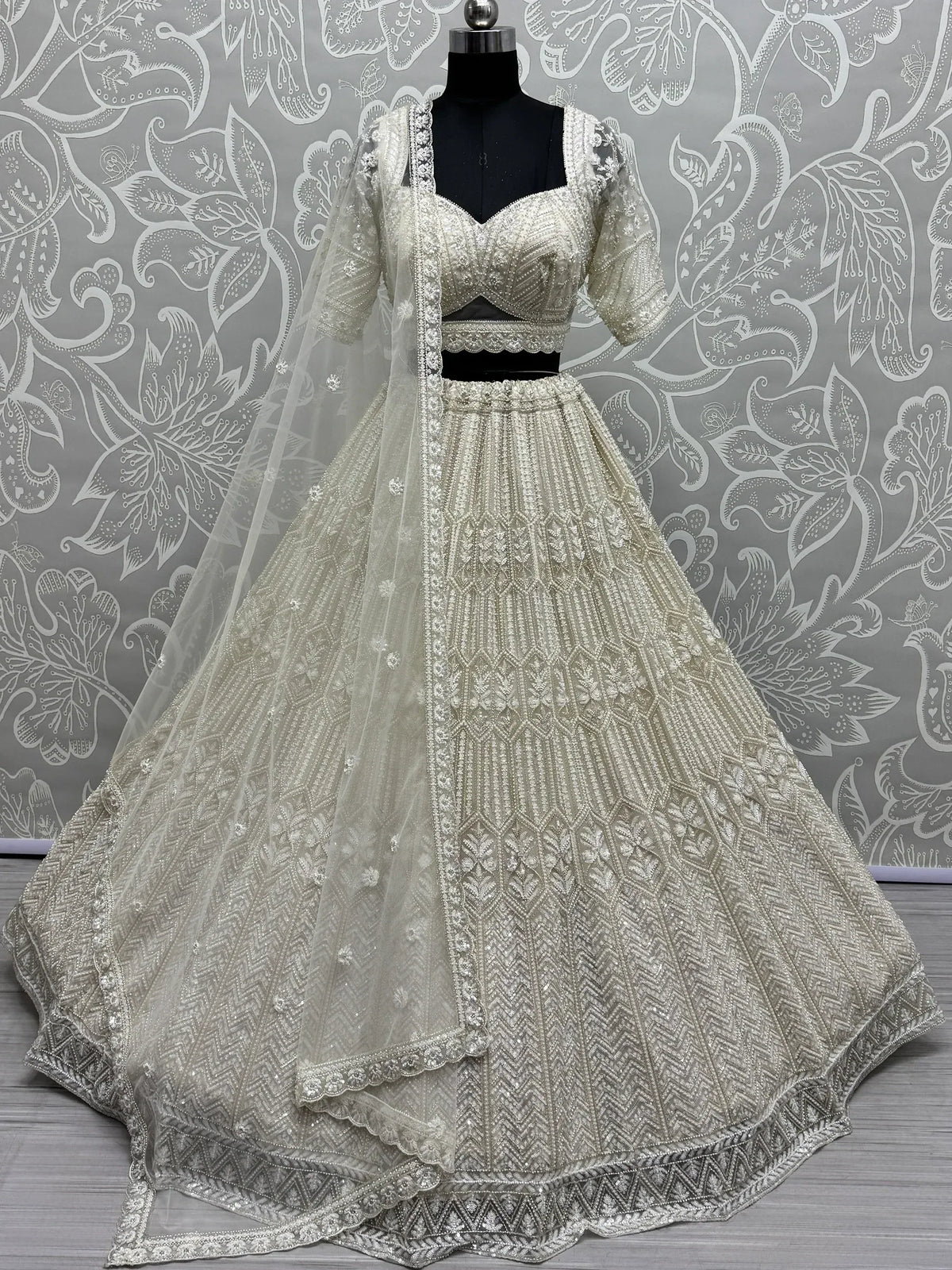 Elegant ivory lehenga choli with heavy embroidery and sheer dupatta, perfect for weddings and festive occasions.