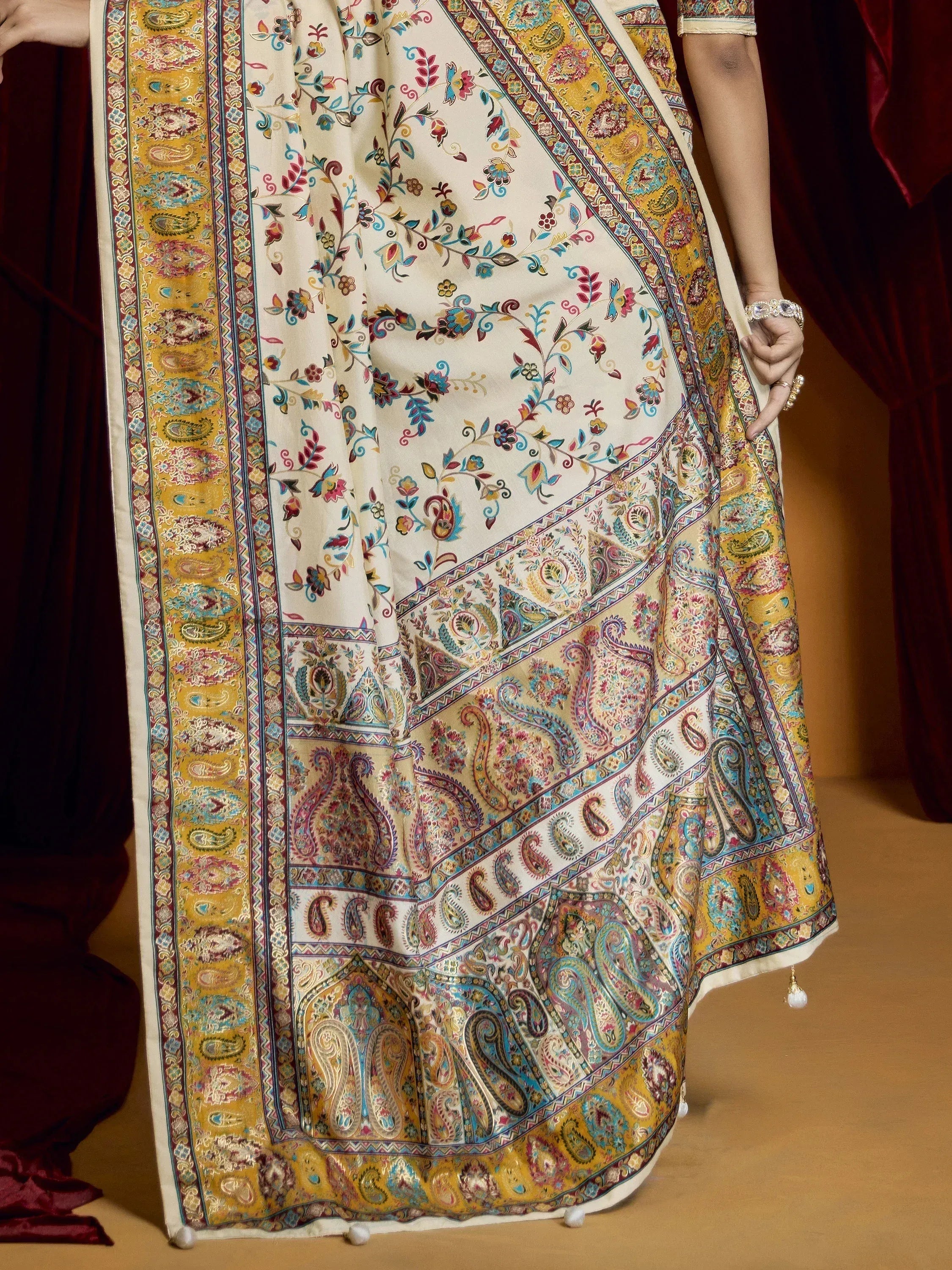 Elegant cream saree with vibrant paisley and floral prints, perfect for Indian ethnic wear occasions.