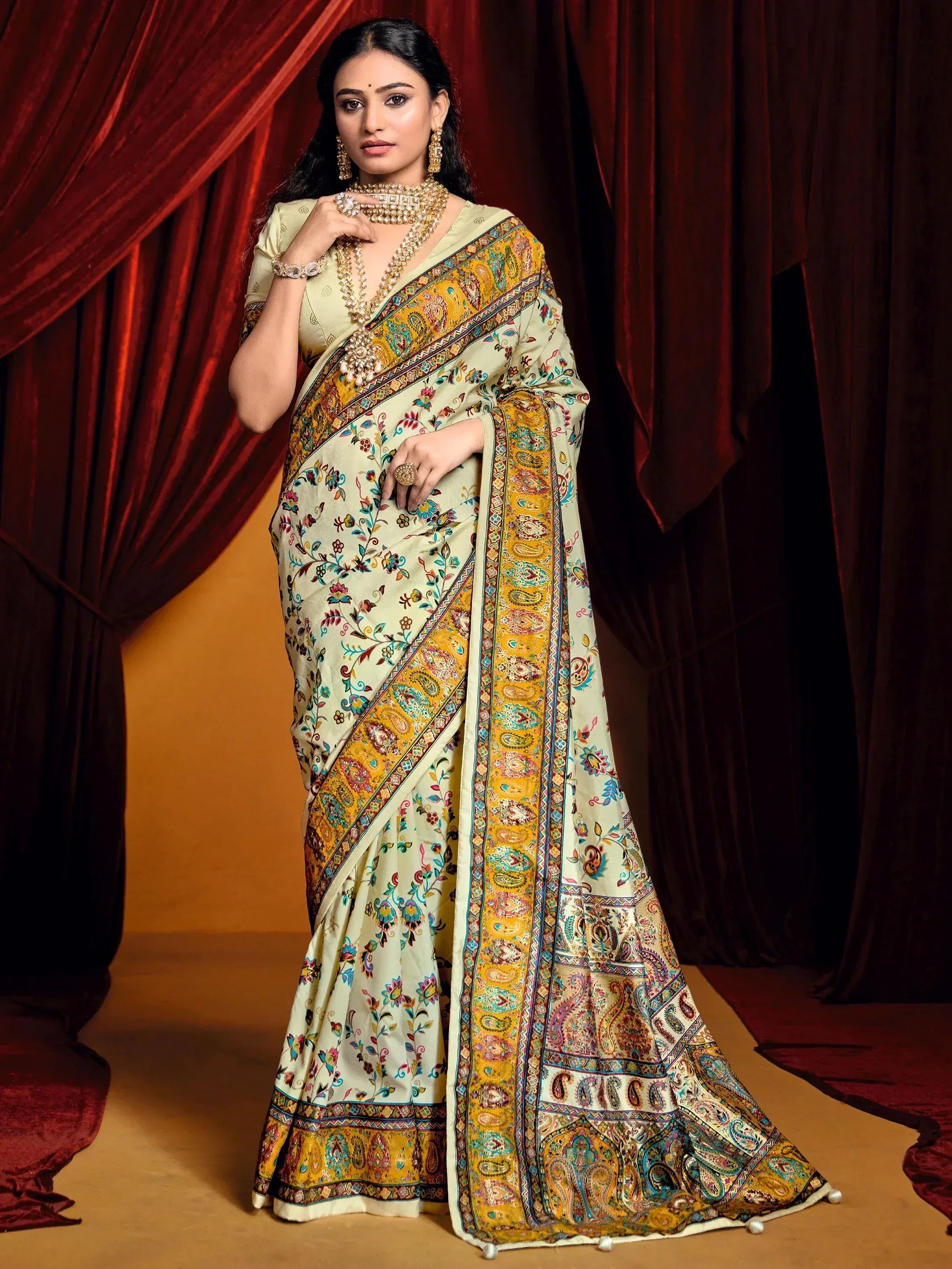 Woman in elegant cream saree with colorful paisley and floral print, perfect for Indian ethnic occasions.