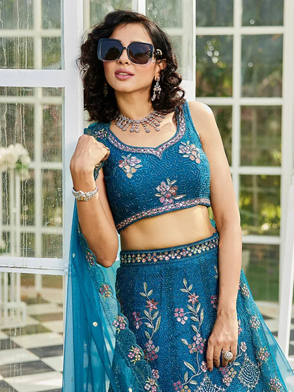 Blue floral embroidered lehenga choli with matching dupatta, styled with sunglasses and jewelry