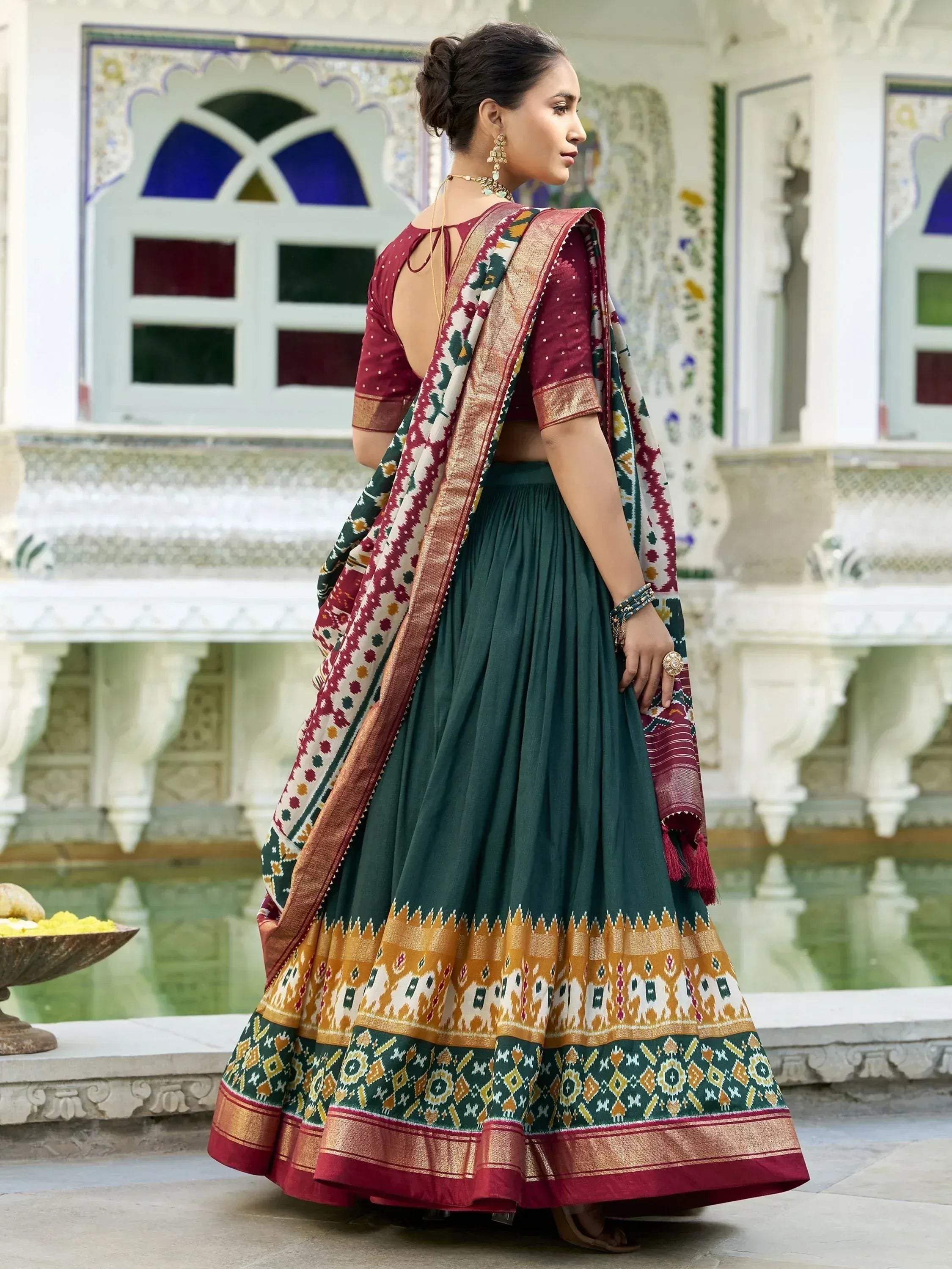 Woman in maroon and green ethnic lehenga choli with ikat dupatta, traditional Indian wear