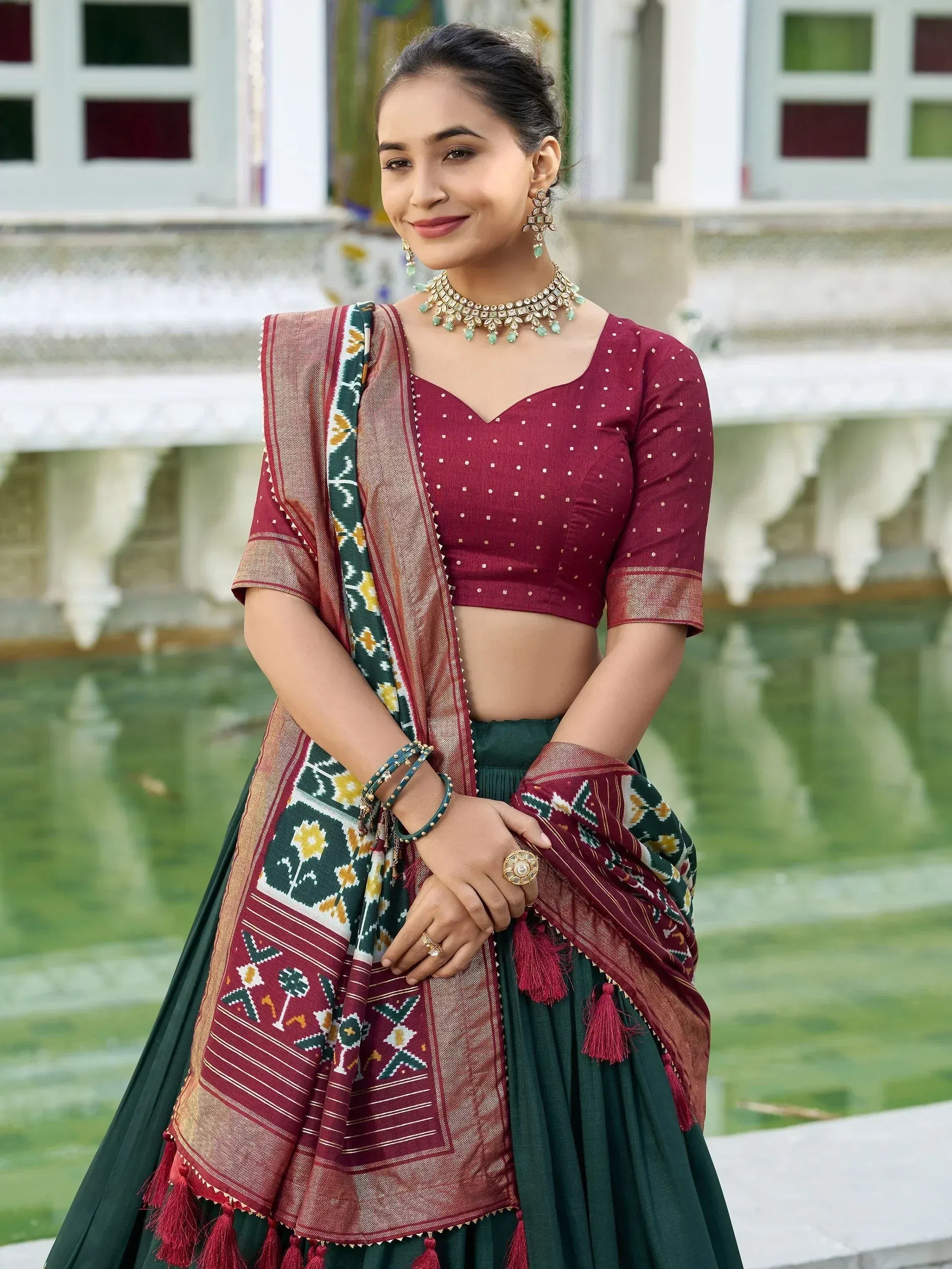 Woman in maroon and green ethnic lehenga choli with printed dupatta, traditional Indian wear for festive occasions