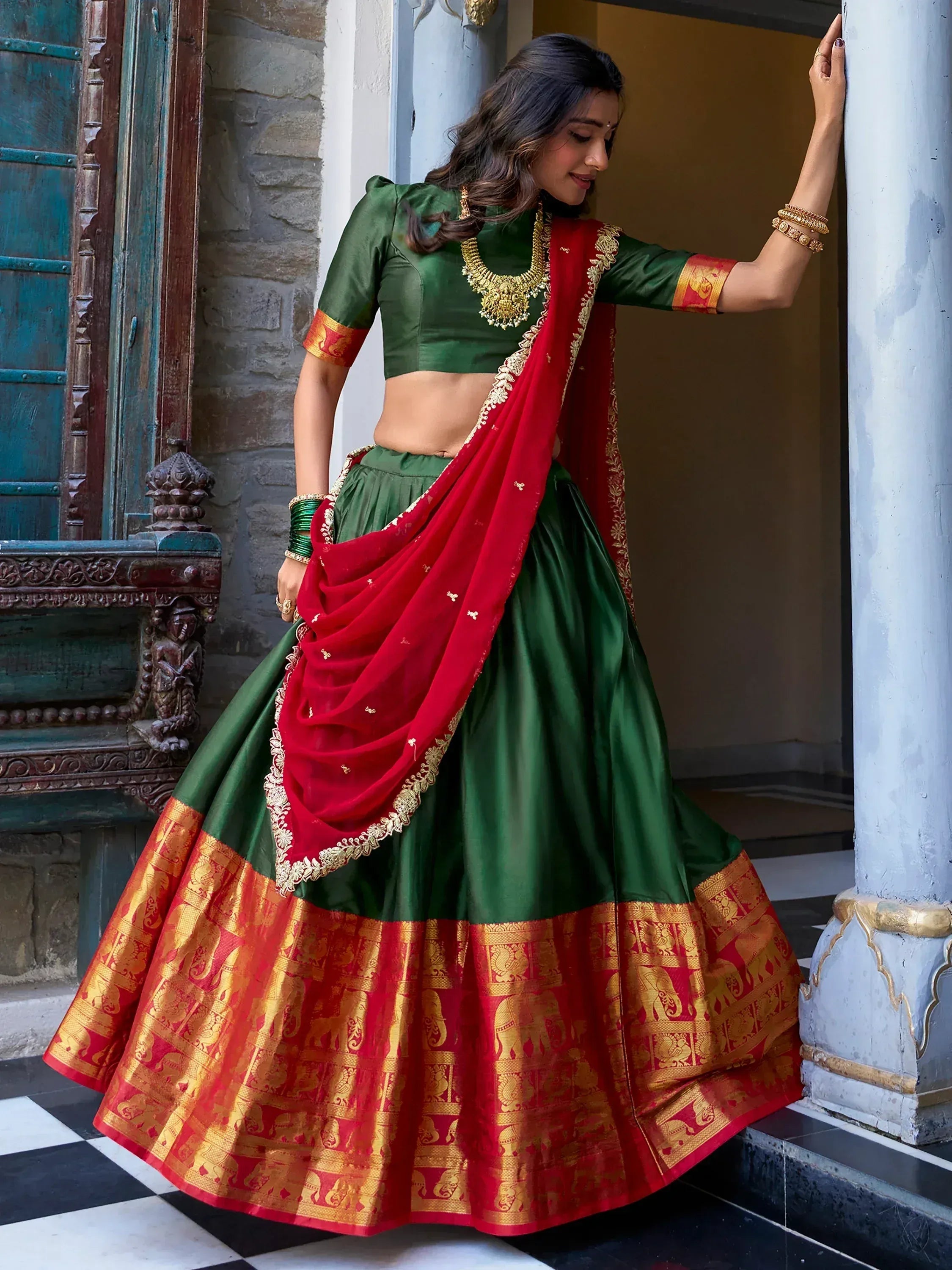 Green and red designer lehenga choli with gold elephant border, perfect for Indian ethnic wear occasions
