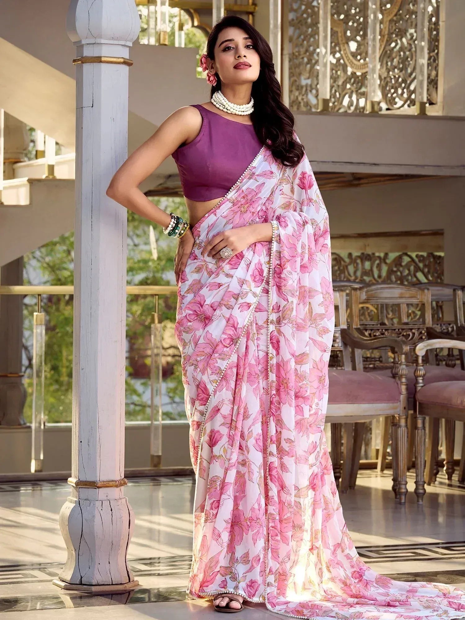 Woman in pink floral saree with purple blouse, pearl jewelry, elegant ethnic wear