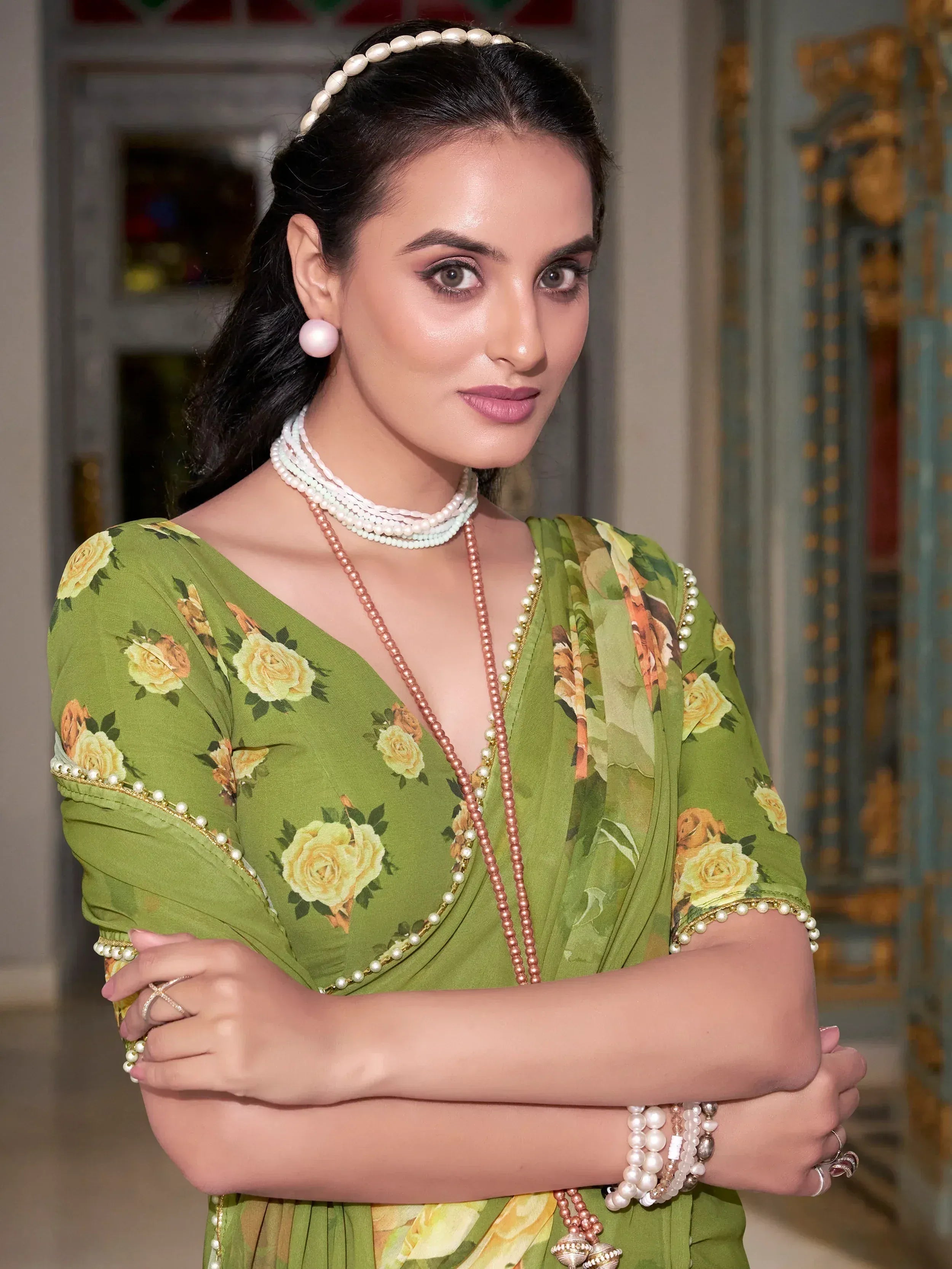 Woman in green floral ethnic gown with pearl jewelry, perfect for Indian occasions and festive wear.