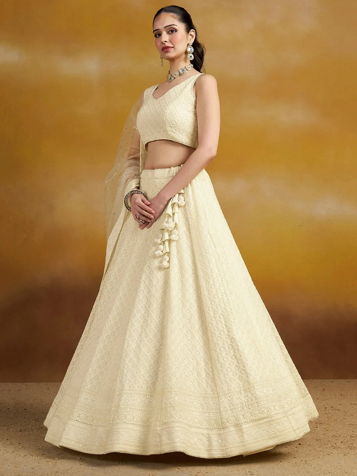Cream embroidered lehenga choli with floral tassels, perfect for Indian weddings and festive occasions.