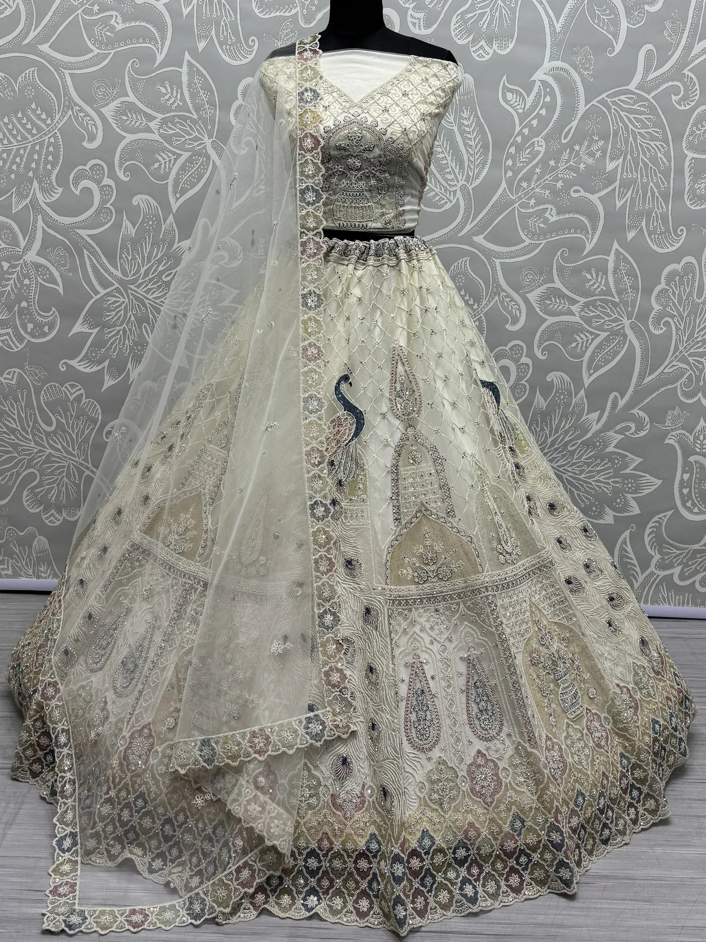 Elegant ivory lehenga choli with peacock embroidery and net dupatta, perfect for Indian weddings and festive occasions.