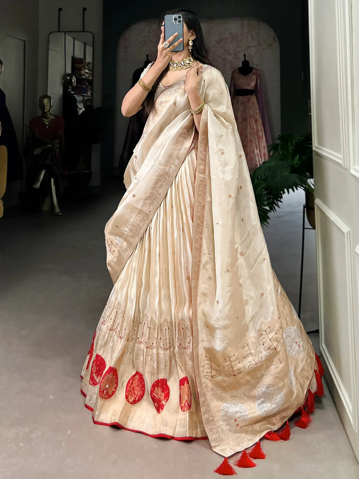 Cream and red embroidered lehenga choli with tassels, perfect for Indian ethnic wear occasions.
