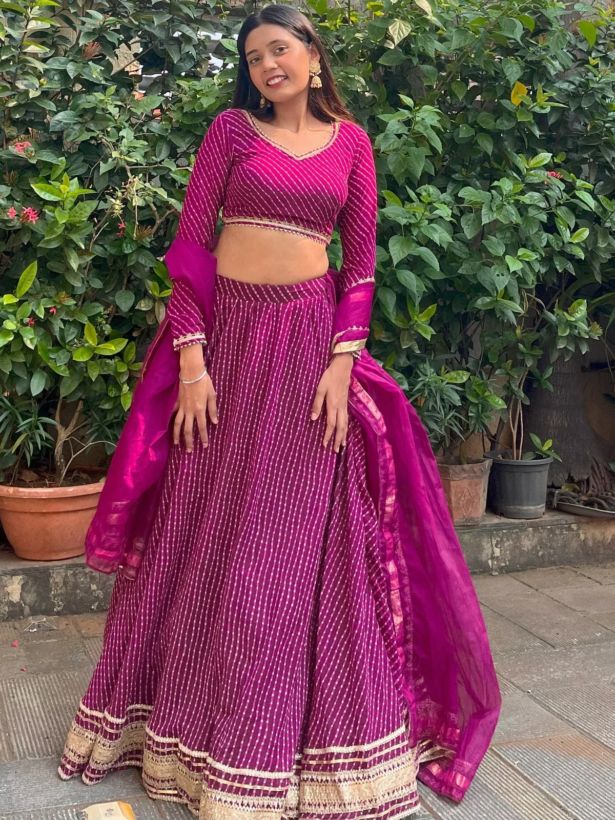 Woman in vibrant magenta lehenga choli with gold trim, perfect for Indian ethnic occasions