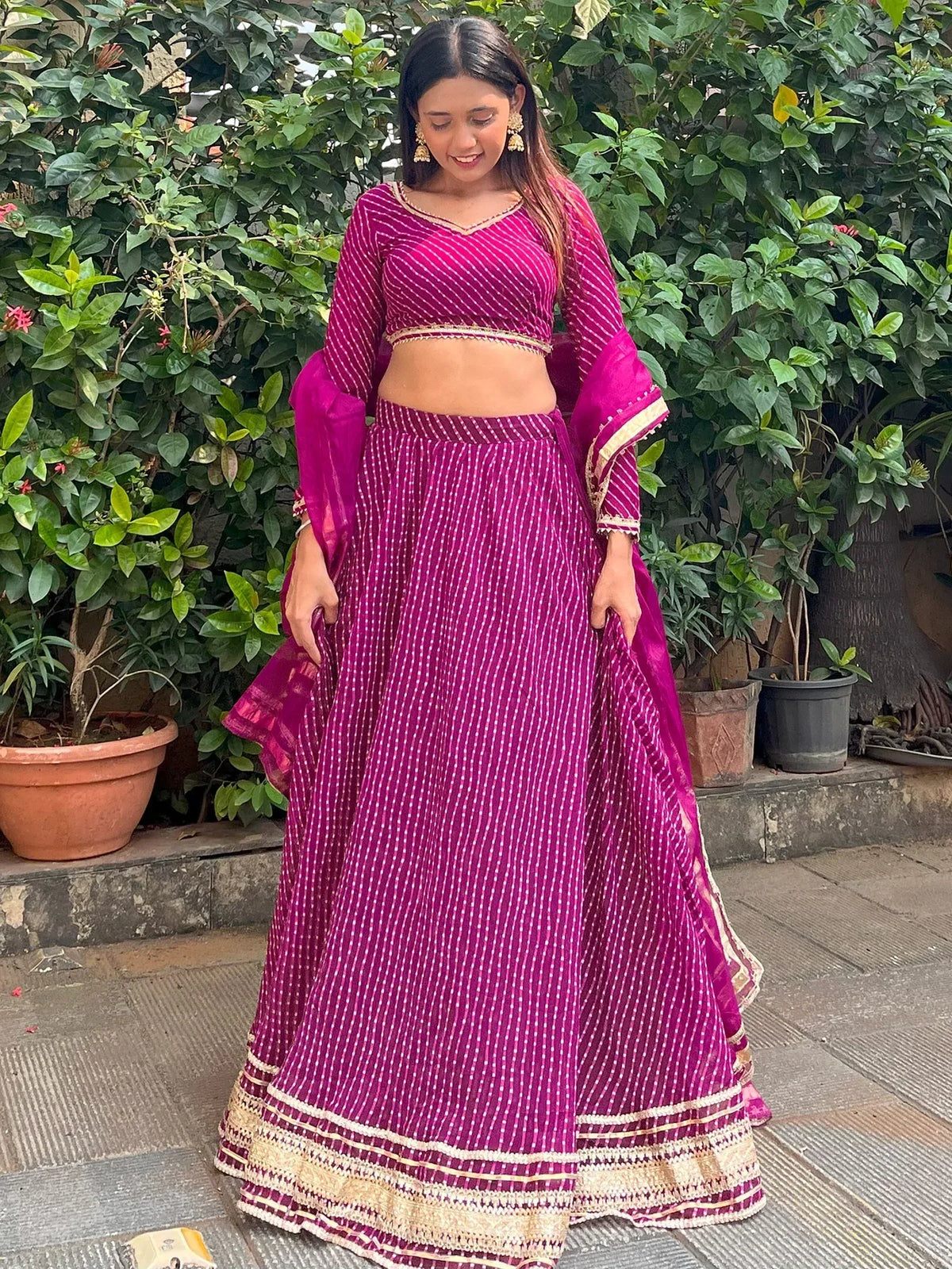 Woman in vibrant magenta lehenga choli with gold trim, perfect for Indian ethnic wear occasions