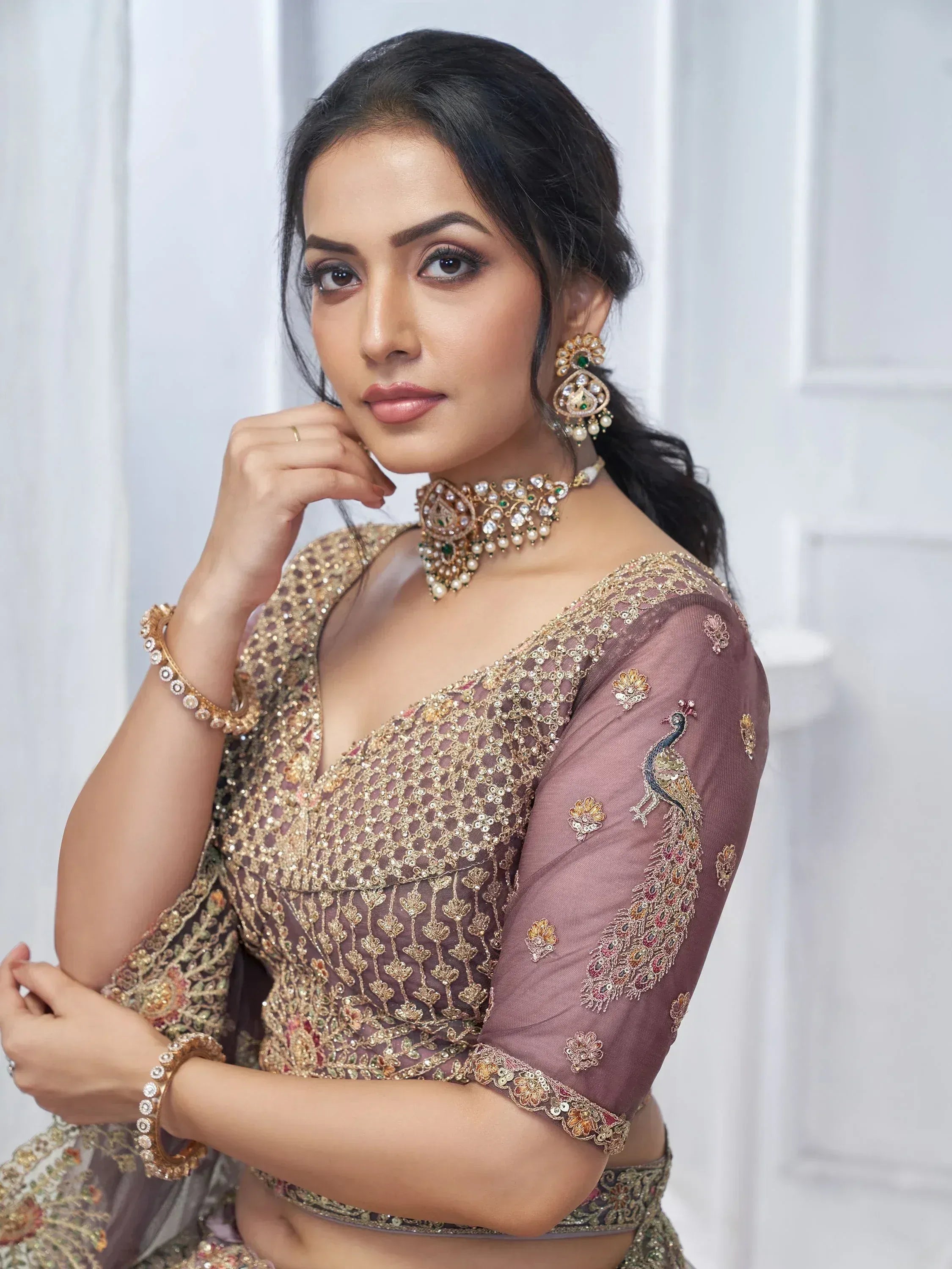 Elegant Indian ethnic blouse with peacock embroidery, gold sequins, and traditional jewelry for festive occasions