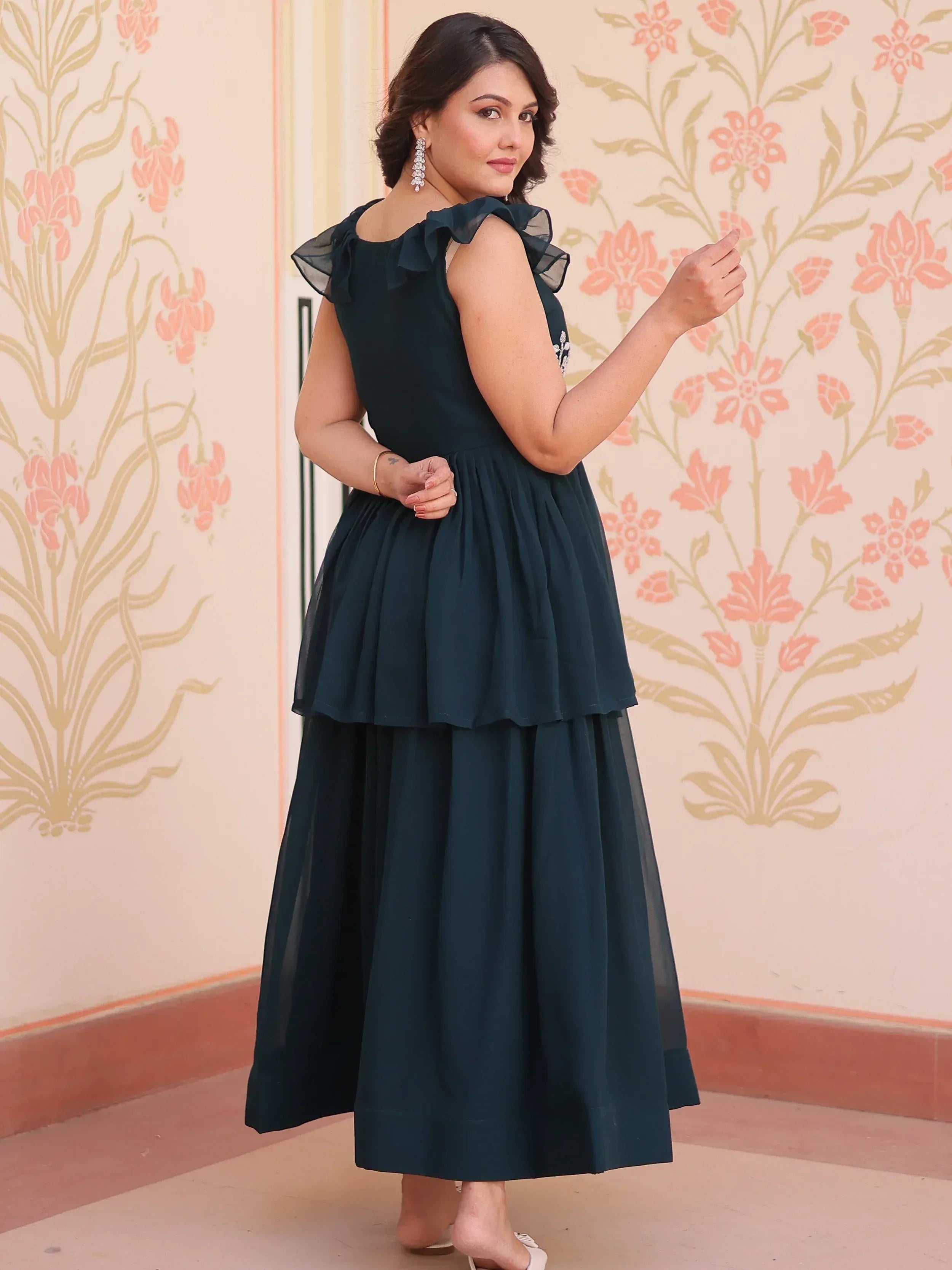 Woman in dark green ethnic gown with ruffle sleeves and layered skirt, perfect for Indian occasions