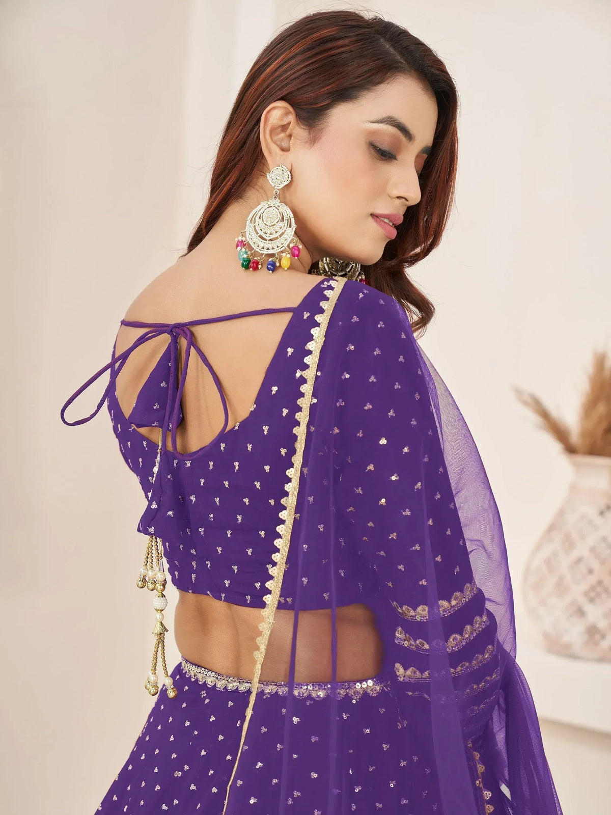Purple designer lehenga choli with gold embroidery, back tie blouse, and colorful jhumka earrings