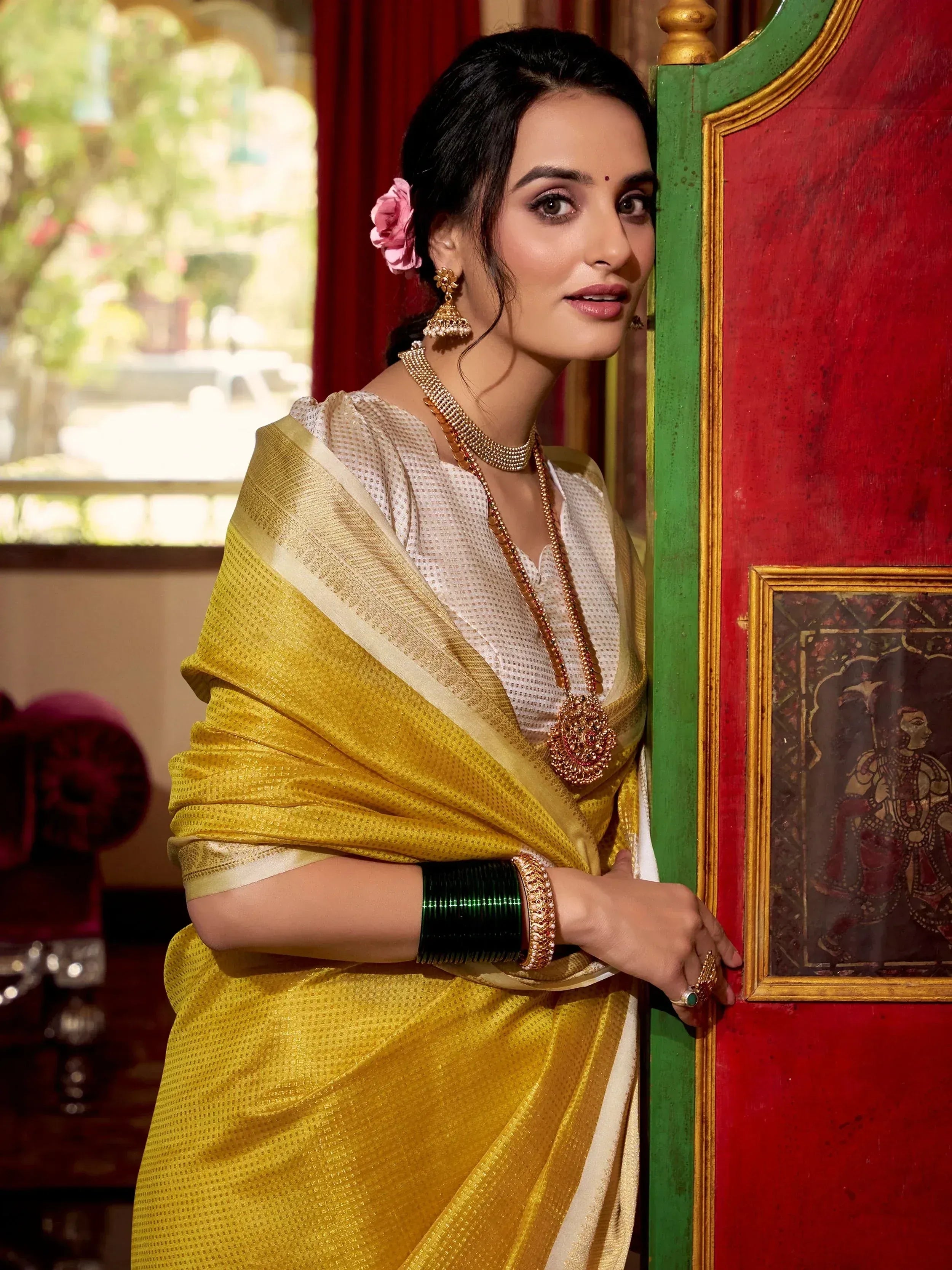 Woman in yellow ethnic saree with gold jewelry, traditional Indian attire for festive occasions