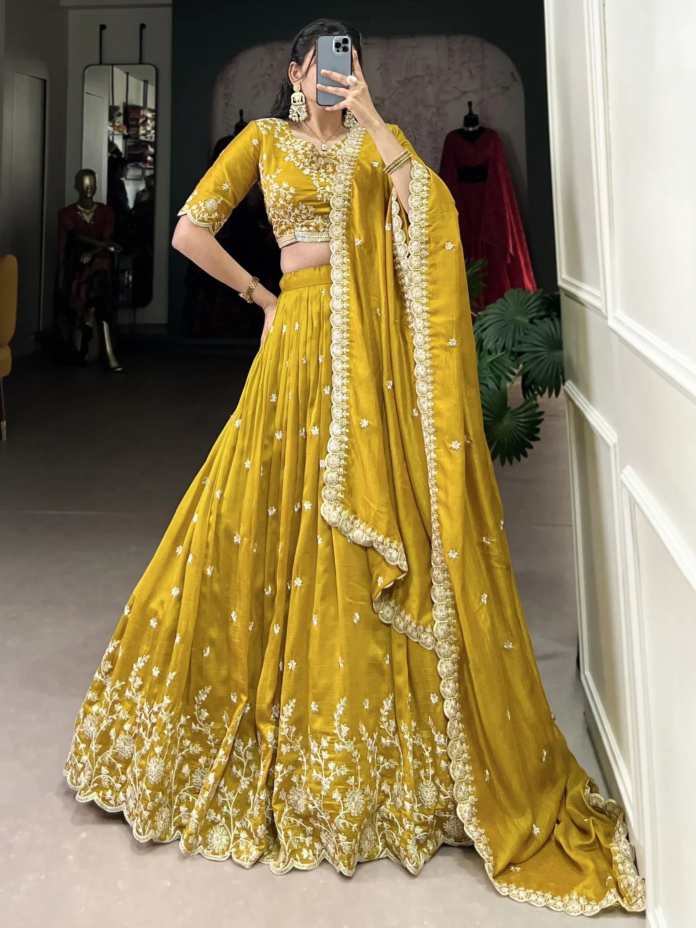 Mustard yellow designer lehenga choli with white floral embroidery and scalloped dupatta, perfect for Indian weddings or festive occasions.