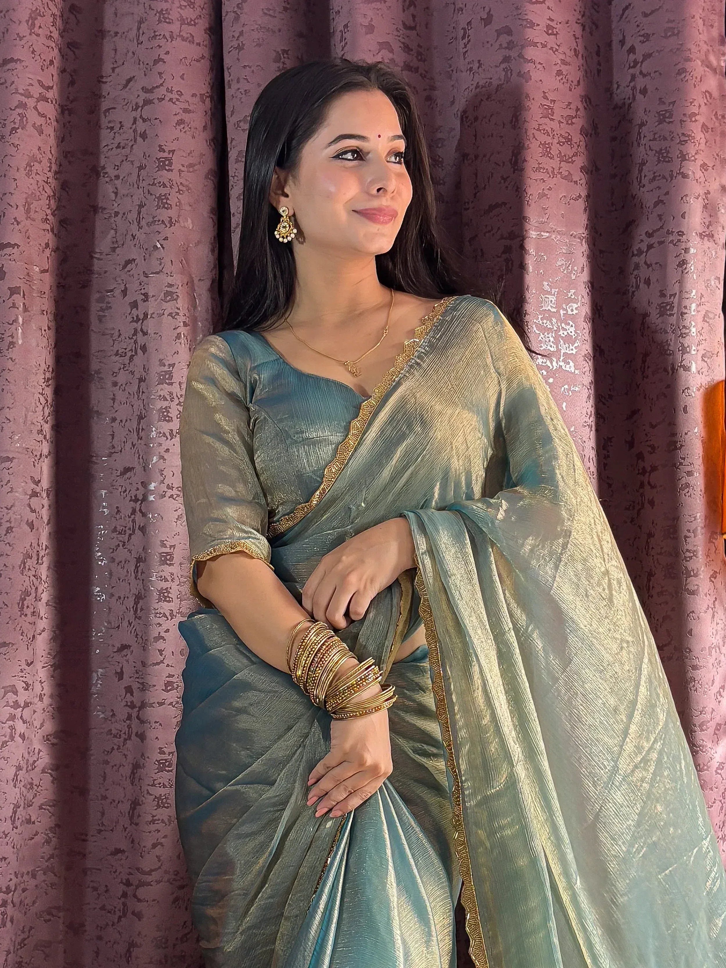 Woman in elegant teal saree with gold border, traditional Indian ethnic wear, styled with bangles and earrings