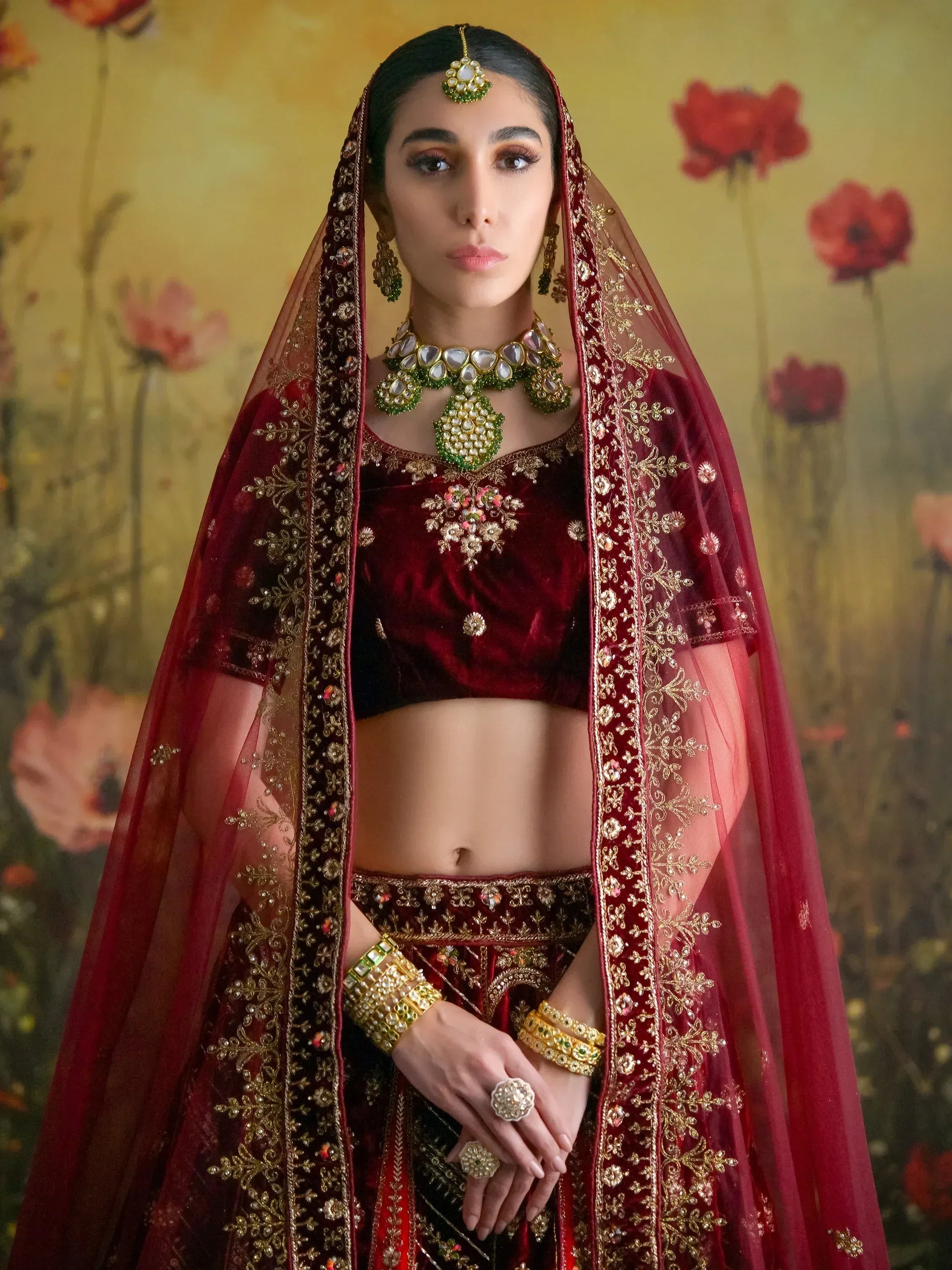 Maroon velvet lehenga choli with gold embroidery and matching dupatta, styled with traditional Indian jewelry.
