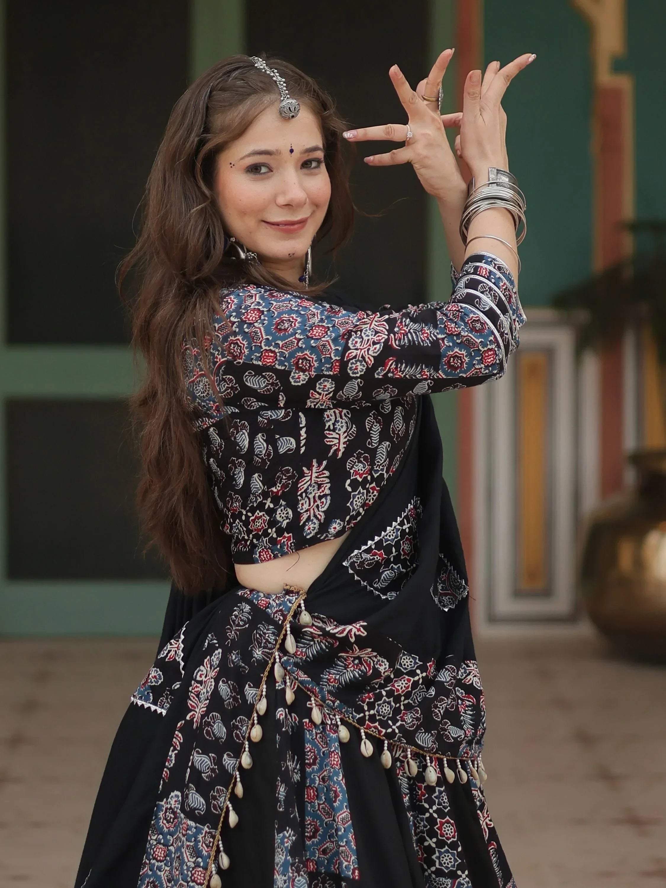 Woman in black floral Indian ethnic wear with traditional jewelry, posing gracefully