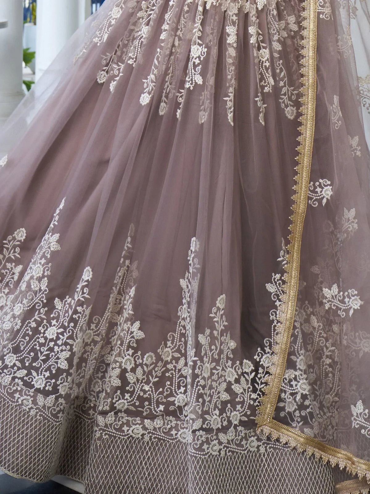 Elegant mauve lehenga with intricate white floral embroidery and gold trim, perfect for Indian ethnic wear.