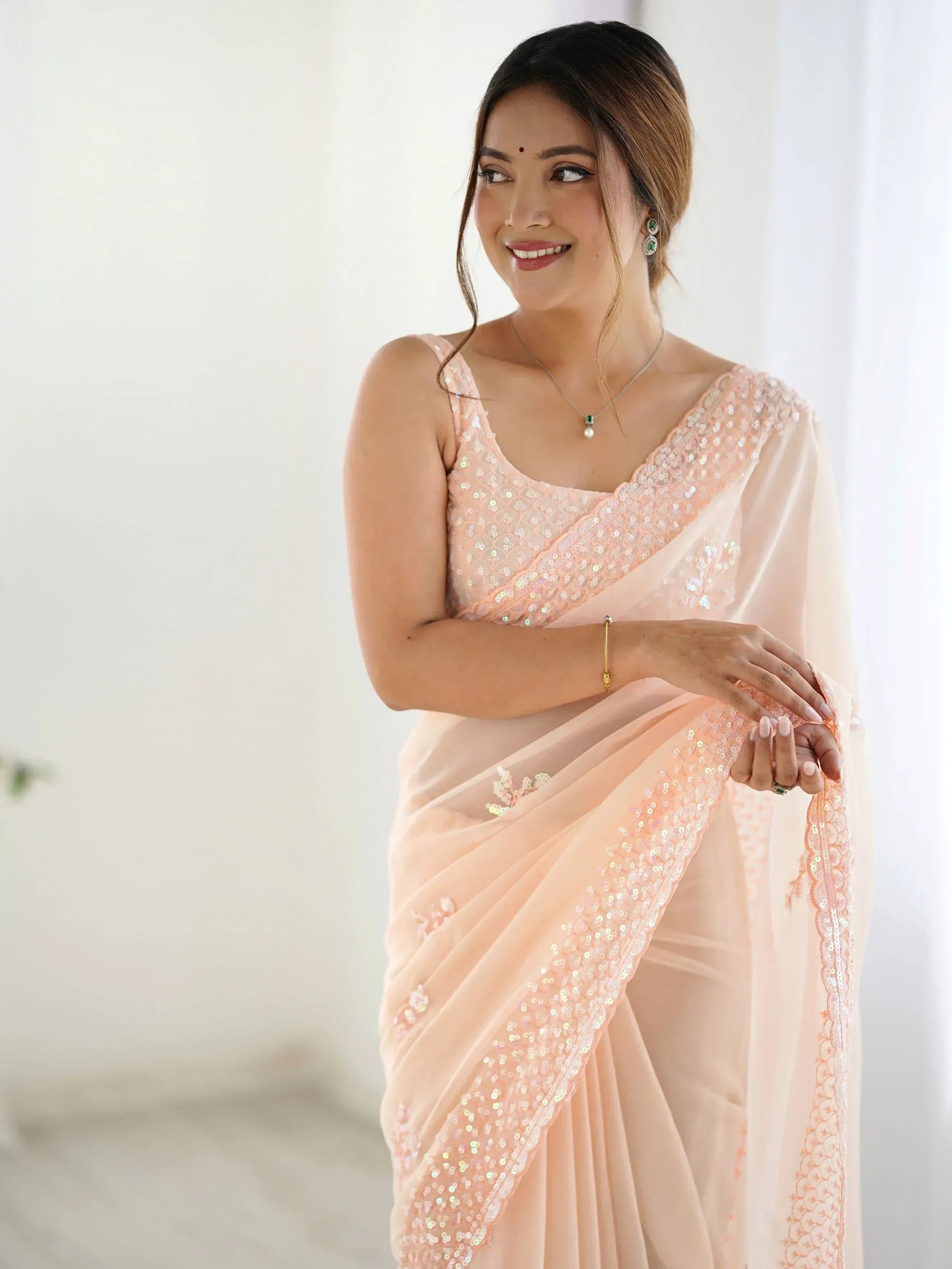 Woman in elegant peach saree with sequin embroidery, perfect for Indian ethnic wear occasions