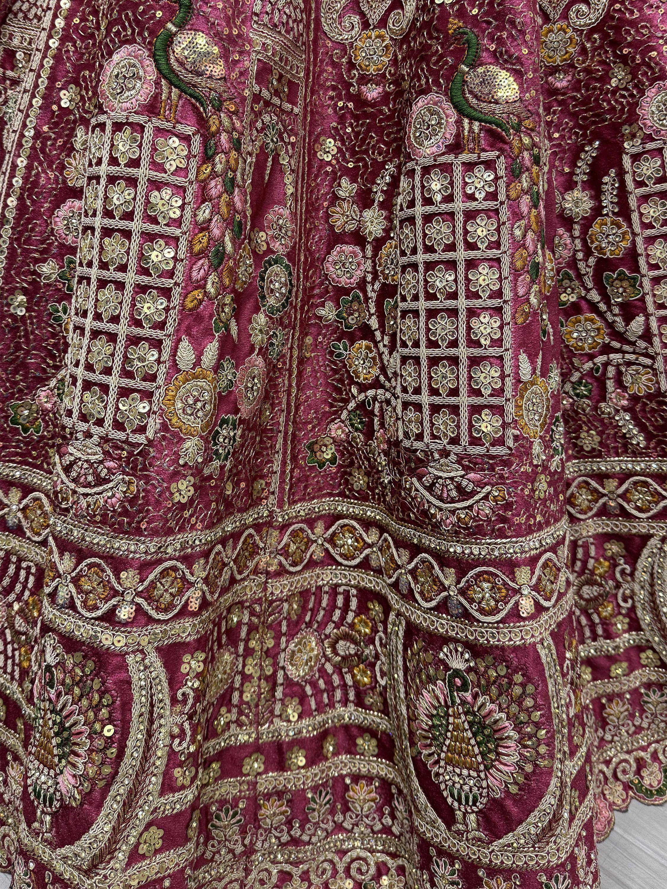 Richly embroidered maroon lehenga with peacock and floral motifs, sequins, and gold thread work