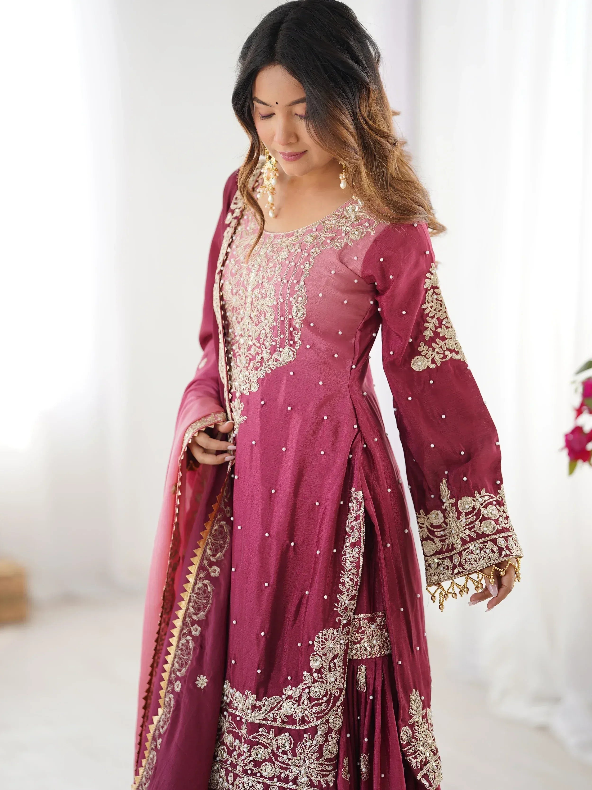 Elegant maroon Indian ethnic gown with gold embroidery and pearl detailing, perfect for festive occasions.