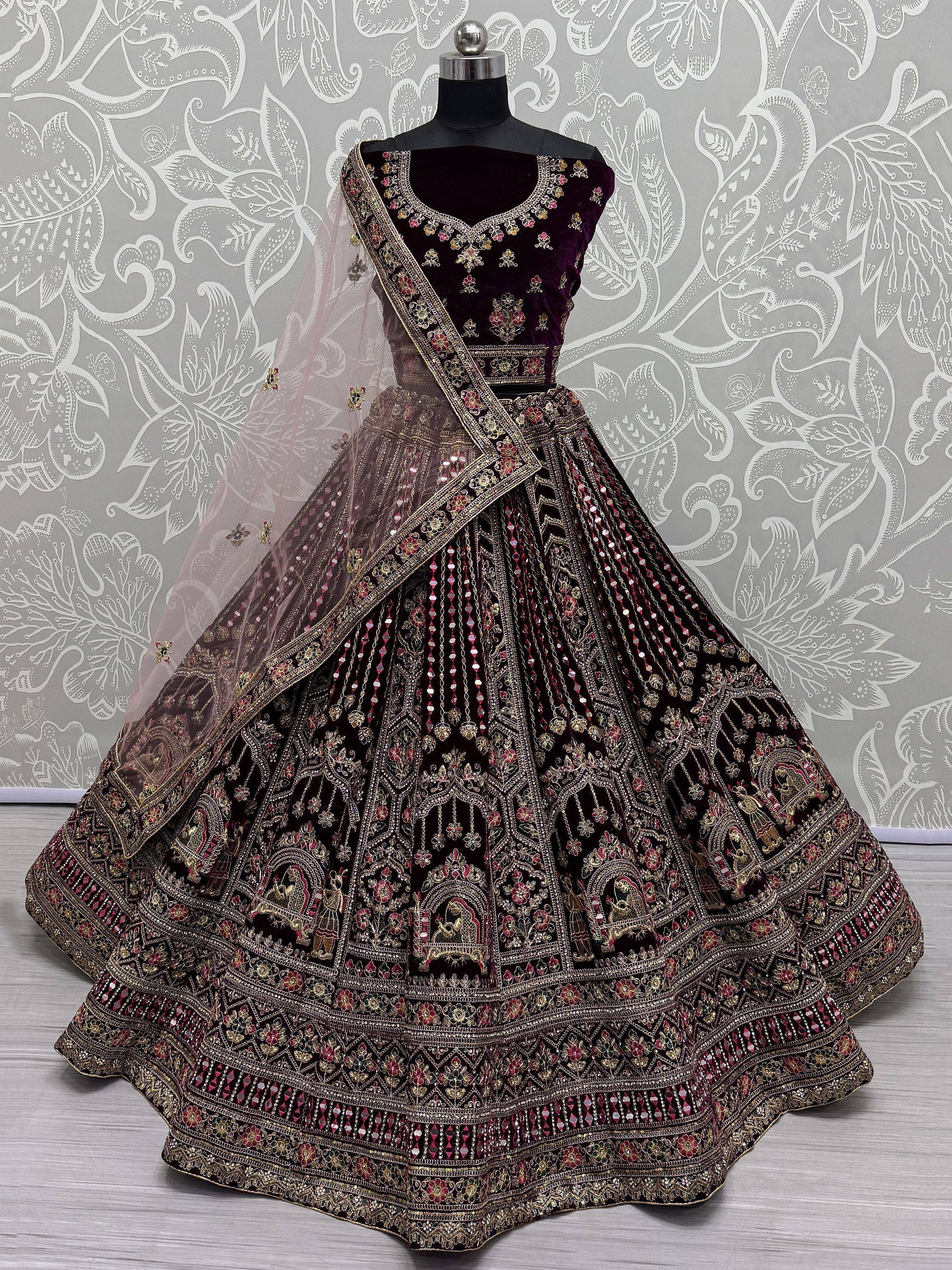 Elegant maroon velvet lehenga choli with heavy gold embroidery and mirror work, perfect for Indian weddings.