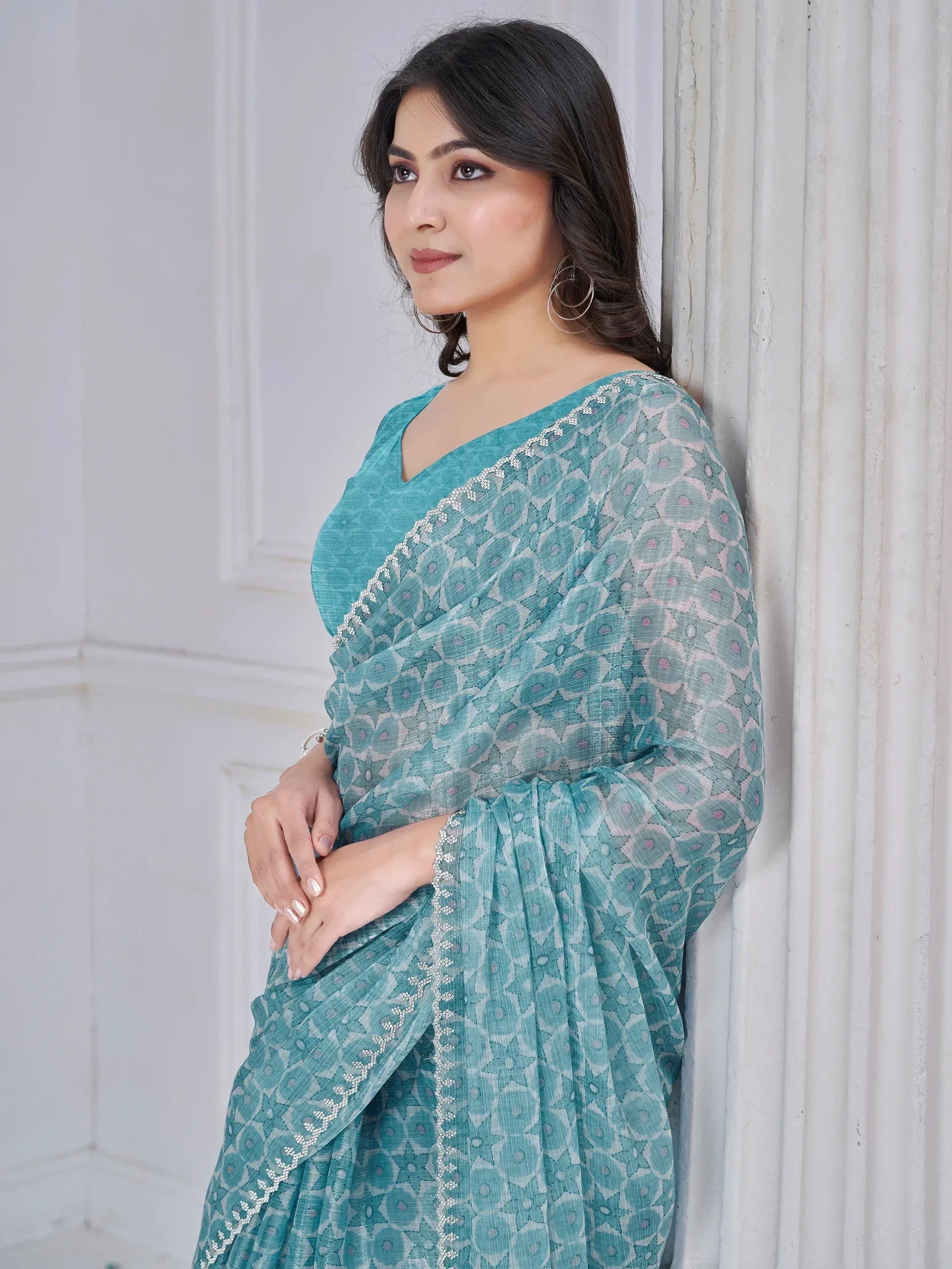 Teal printed saree with floral pattern and silver embroidery, styled with matching blouse for ethnic wear