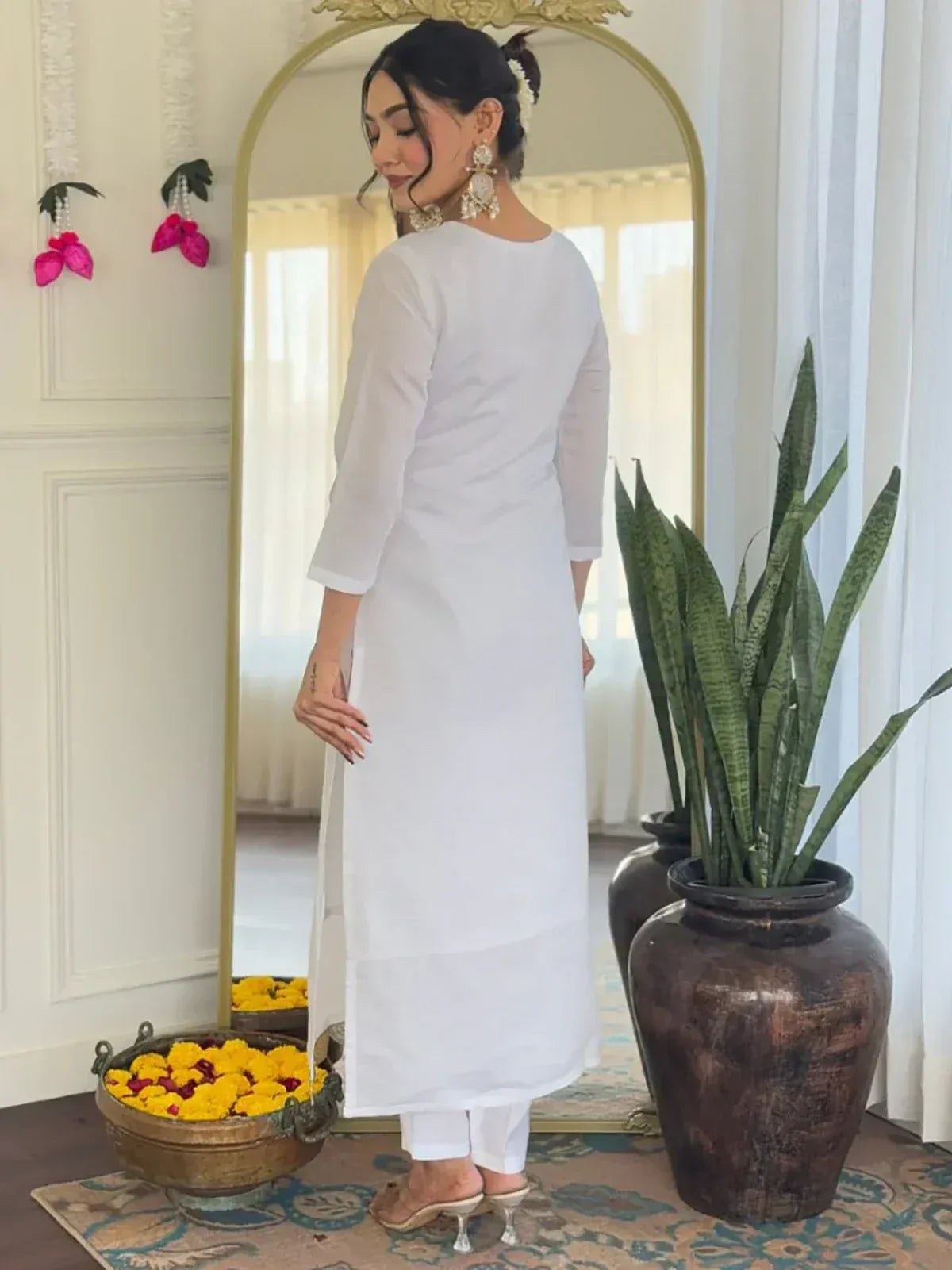 White ethnic kurta with side slit, paired with pants, showcased in elegant indoor setting with mirror and decor