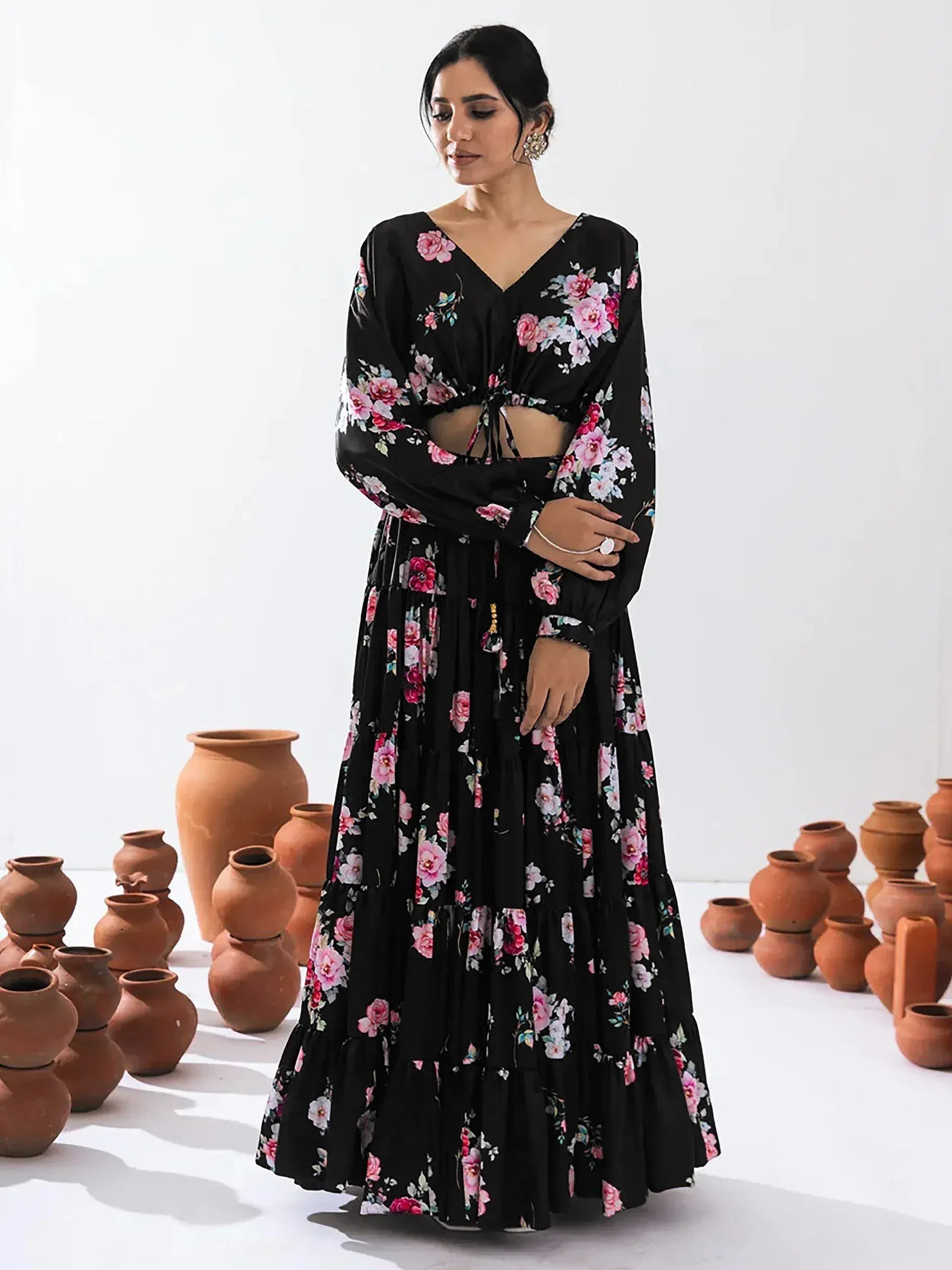Black floral print ethnic gown with tiered skirt and V-neck, styled with clay pots for traditional Indian wear.
