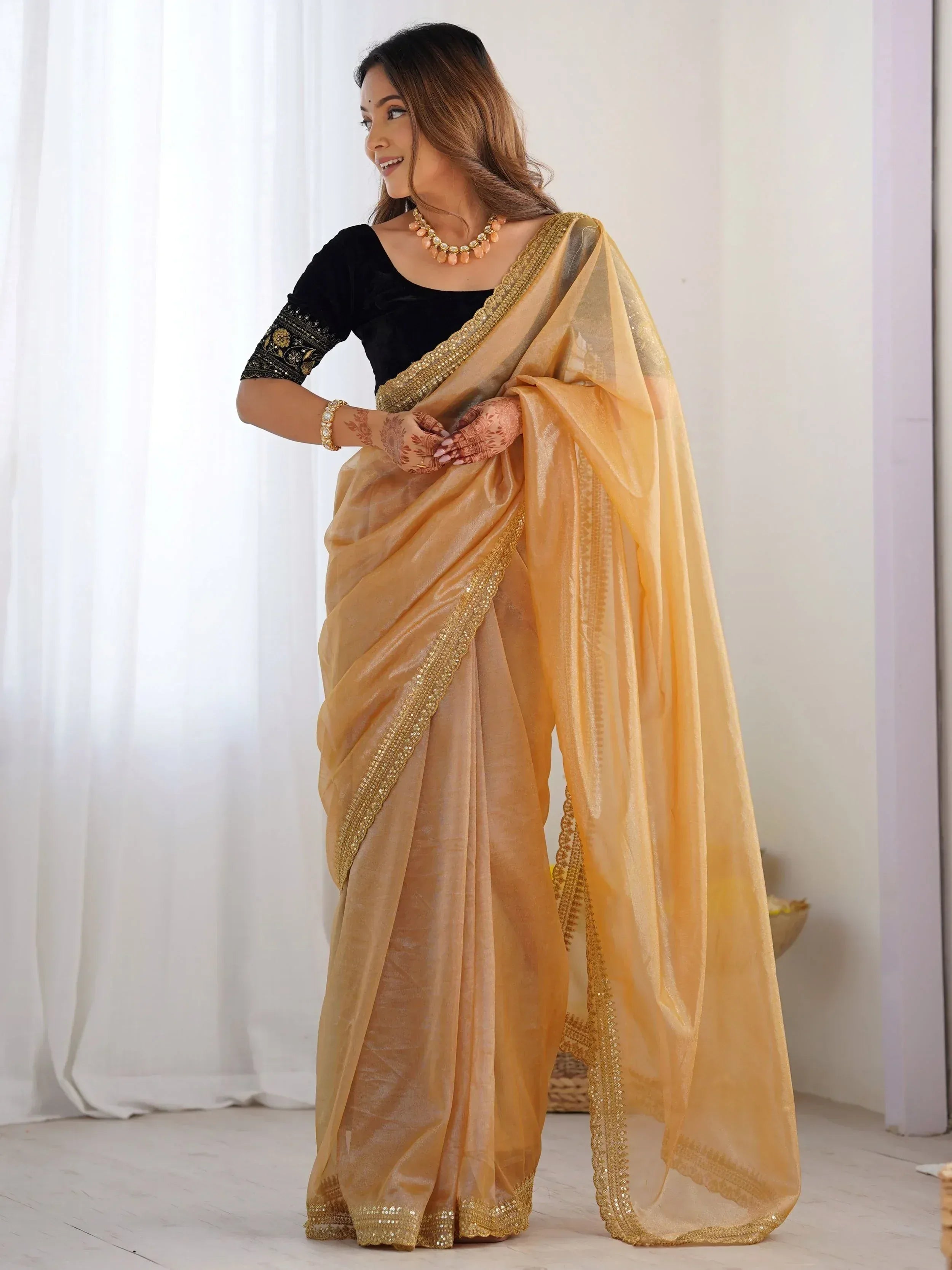 Elegant golden saree with sequin border, paired with black embroidered blouse, perfect for Indian ethnic wear