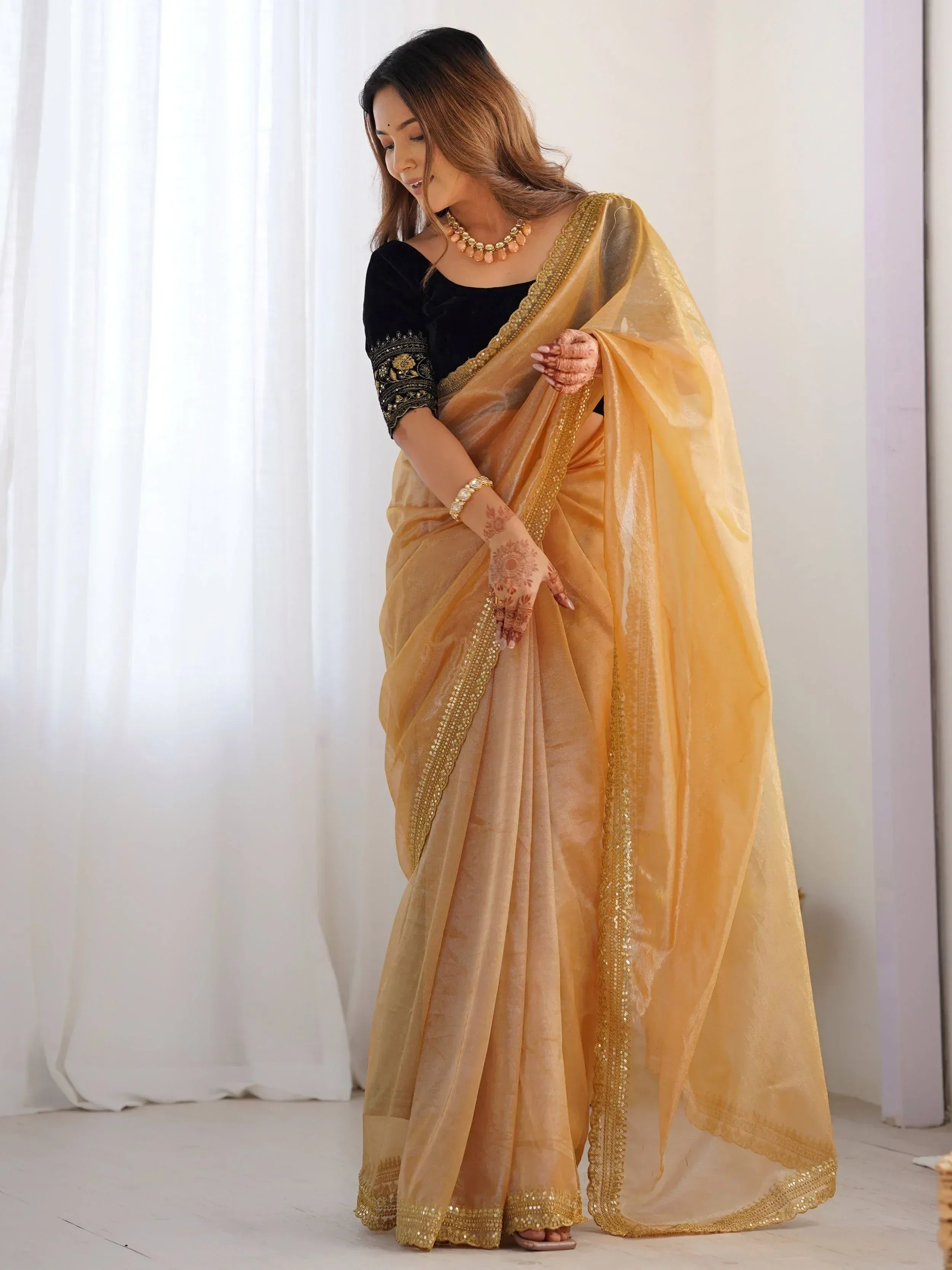 Elegant golden saree with sequin border, paired with black embroidered blouse, perfect for Indian ethnic occasions.