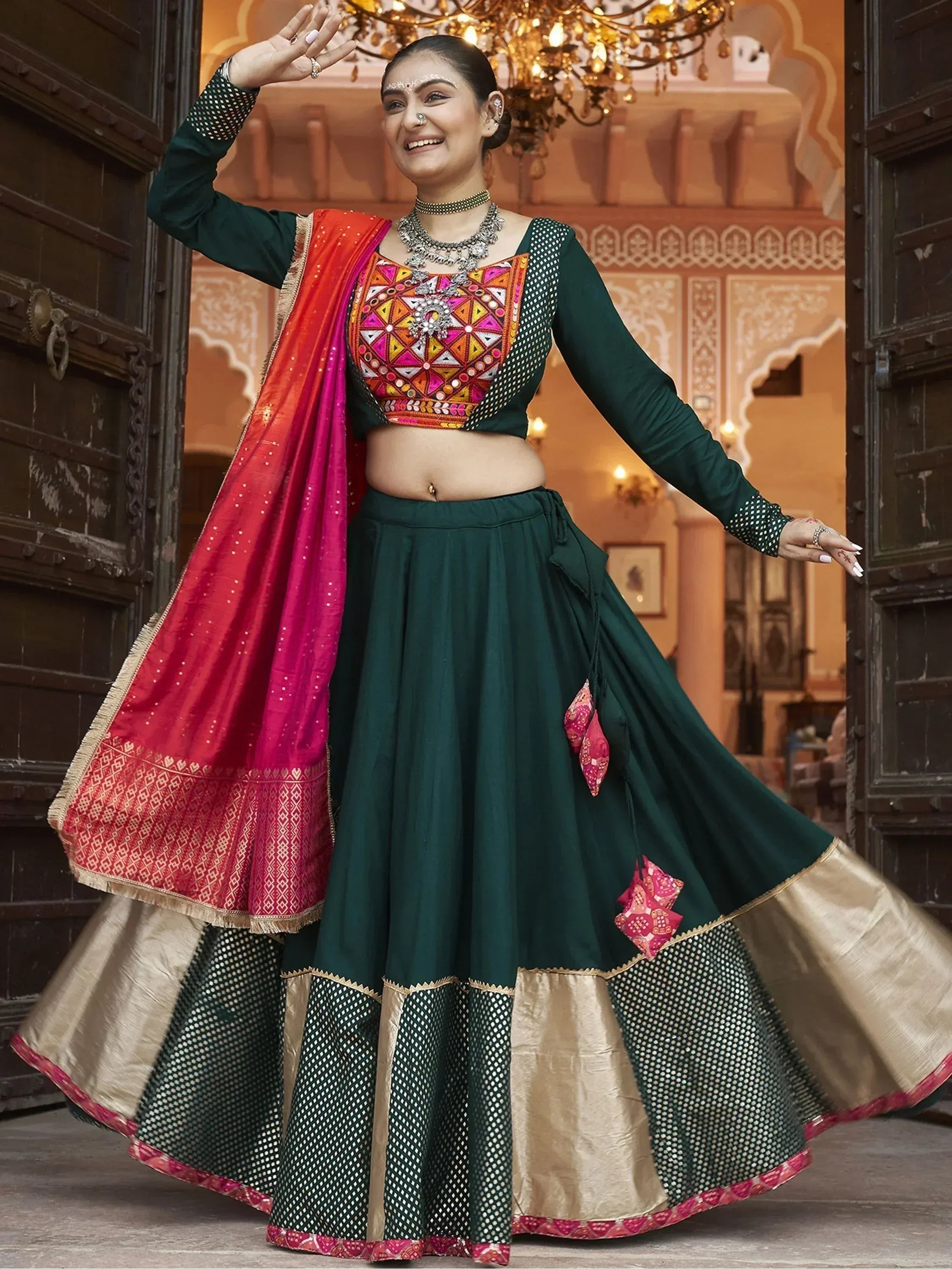 Woman in green embroidered lehenga choli with pink dupatta, traditional Indian ethnic wear