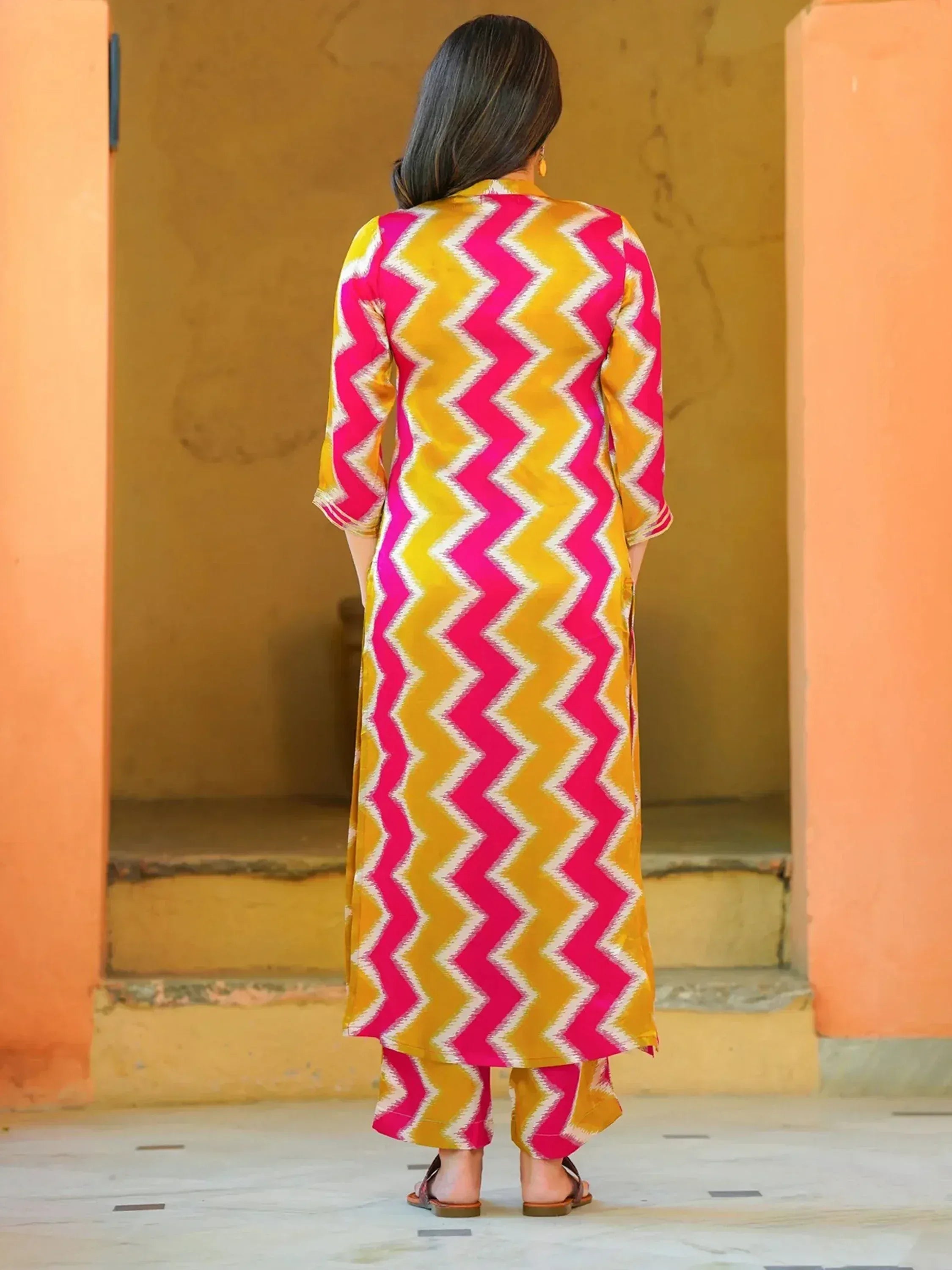 Woman in vibrant pink and yellow zigzag print salwar kameez, ethnic wear for festive occasions