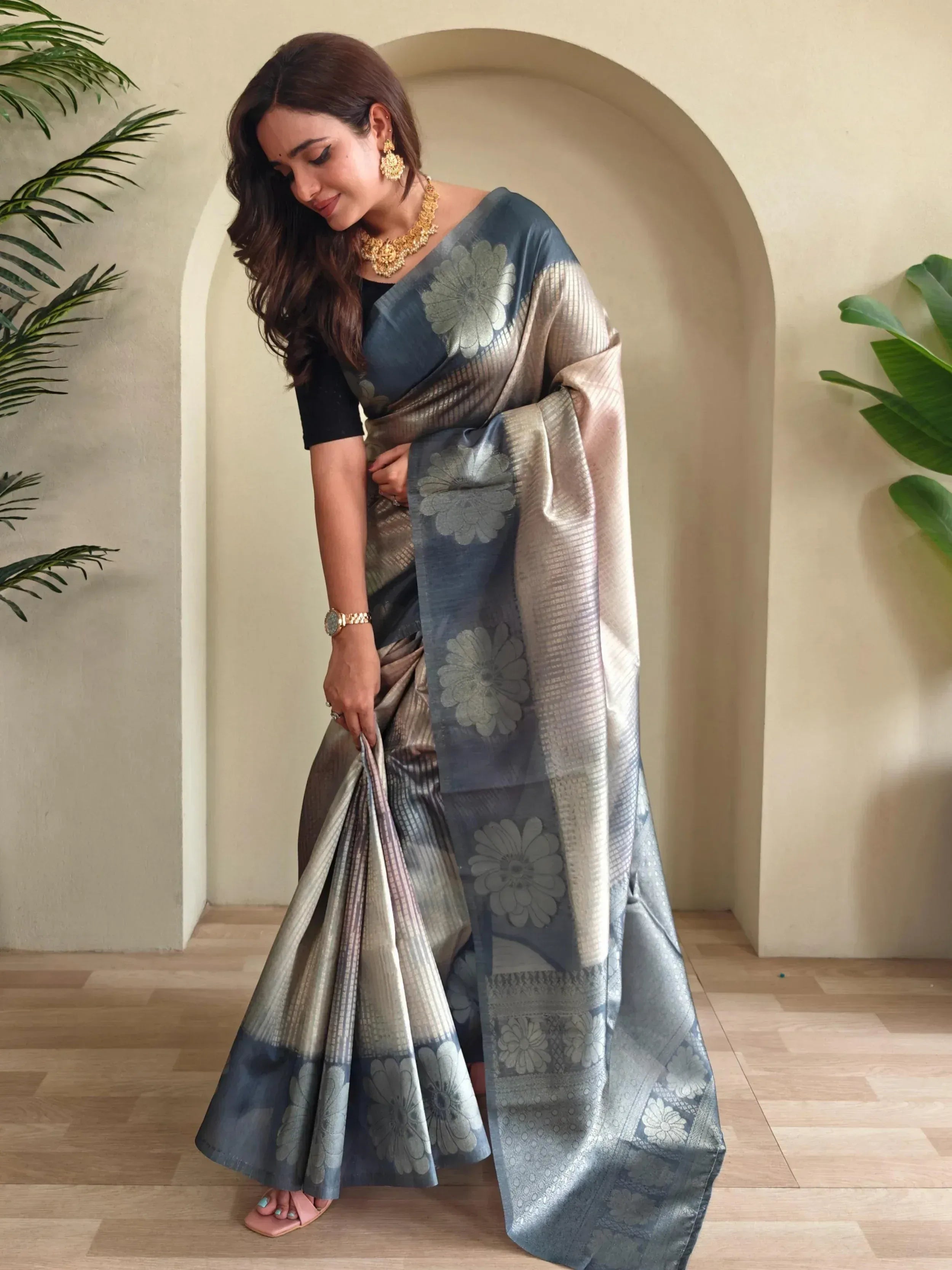 Woman in elegant blue and silver floral saree with gold jewelry, showcasing Indian ethnic wear.