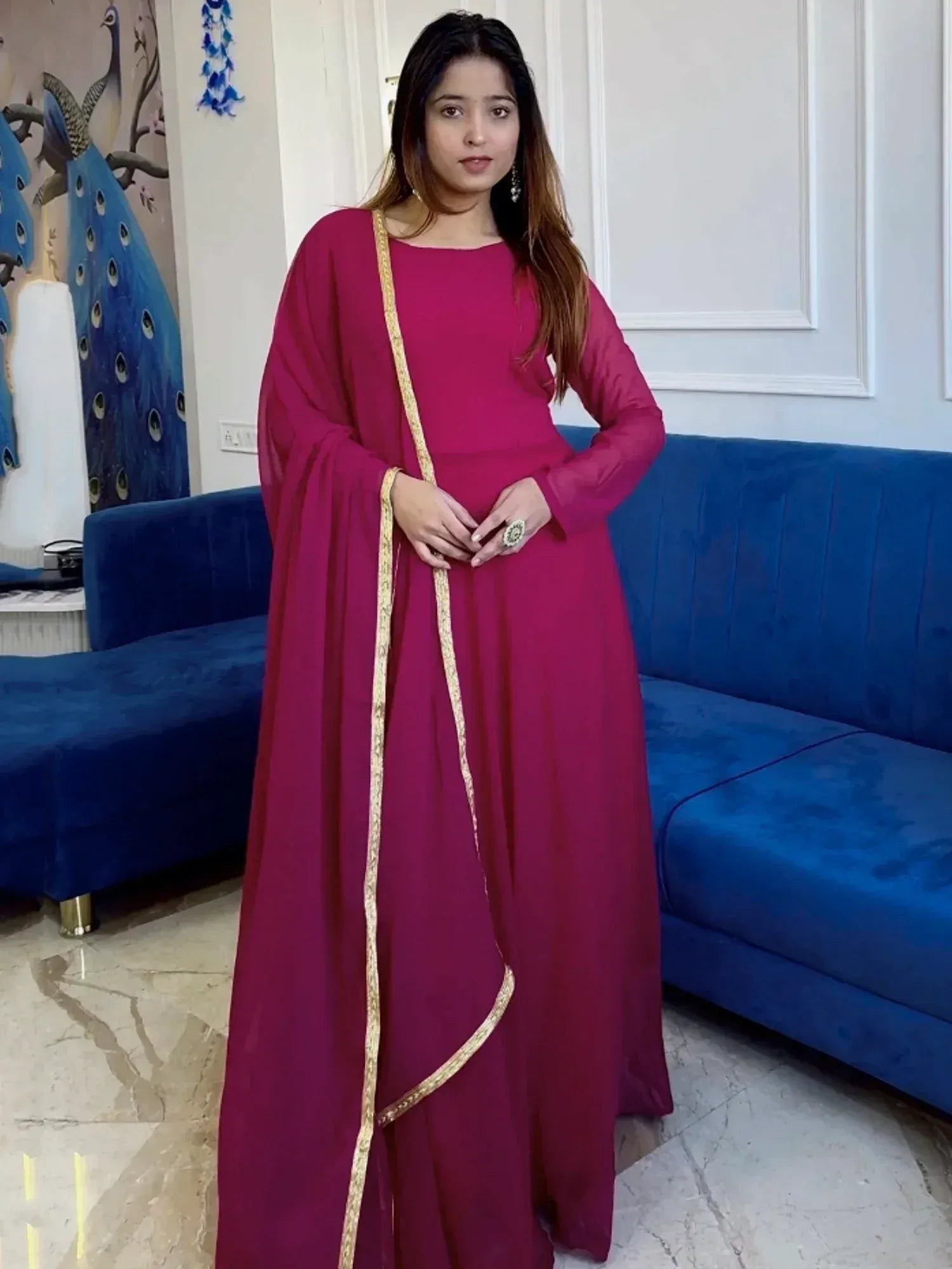 Woman in maroon ethnic gown with gold trim, styled for Indian occasions
