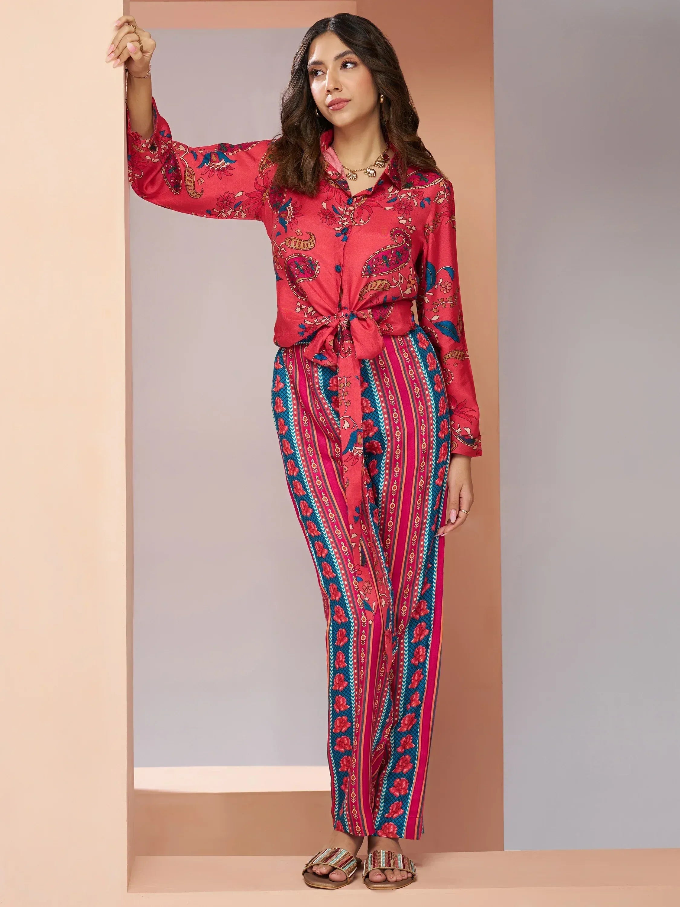 Woman in vibrant red and blue printed ethnic palazzo set with tie-front top, perfect for Indian occasions.