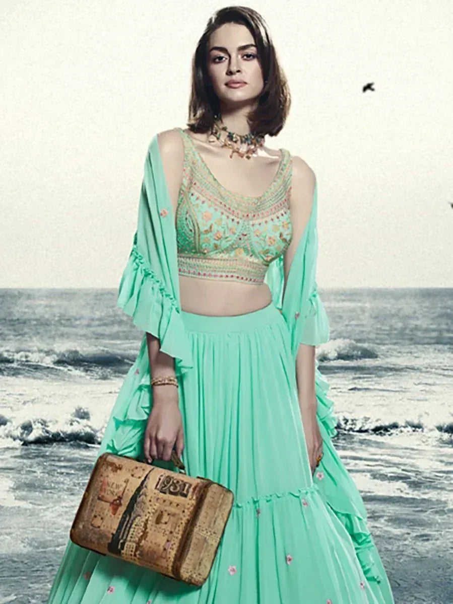 Mint green embroidered lehenga choli with ruffled dupatta, beach backdrop, vintage suitcase accessory