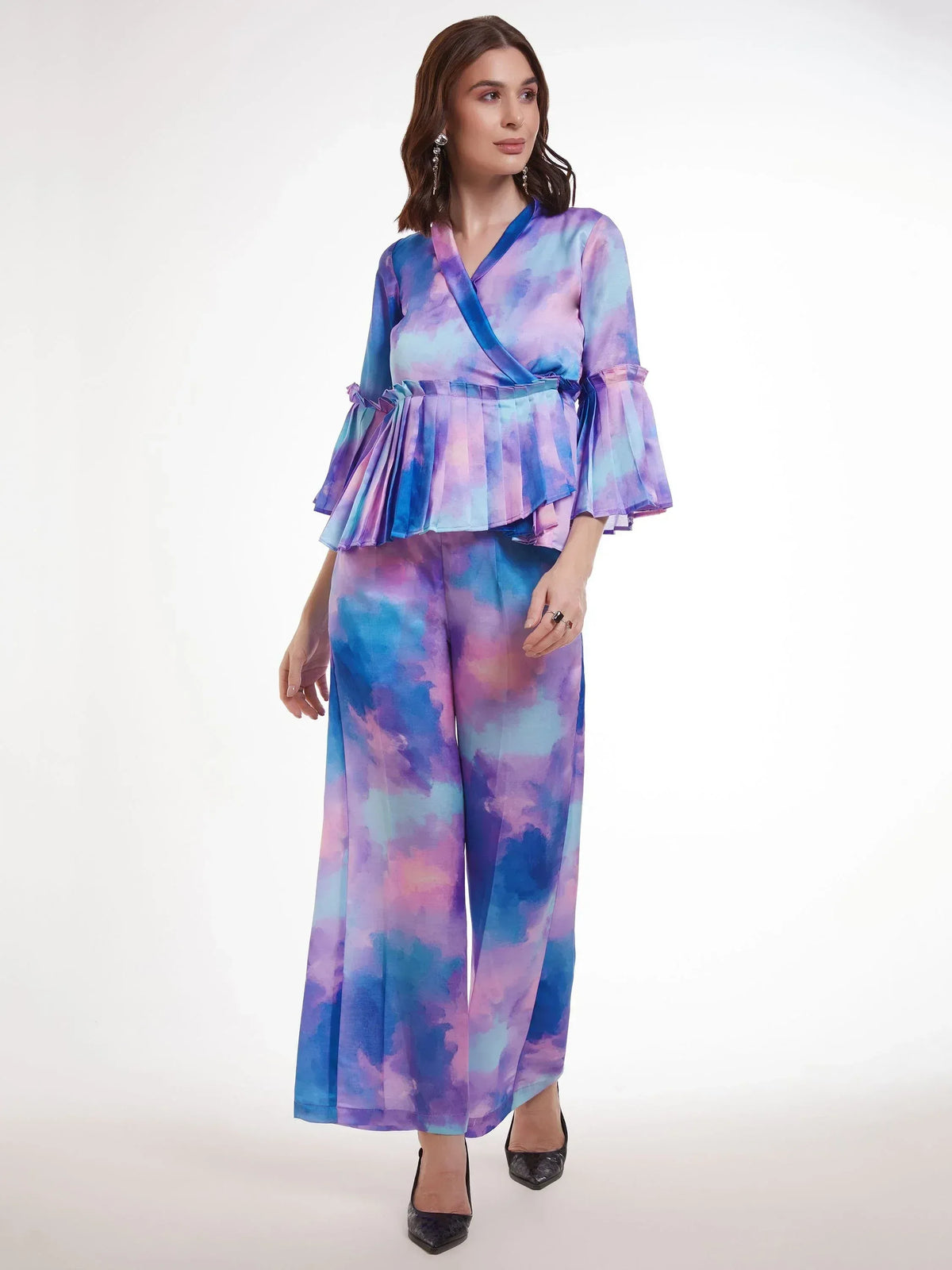 Woman in vibrant tie-dye ethnic palazzo set with ruffled top and wide-leg pants, perfect for festive occasions.