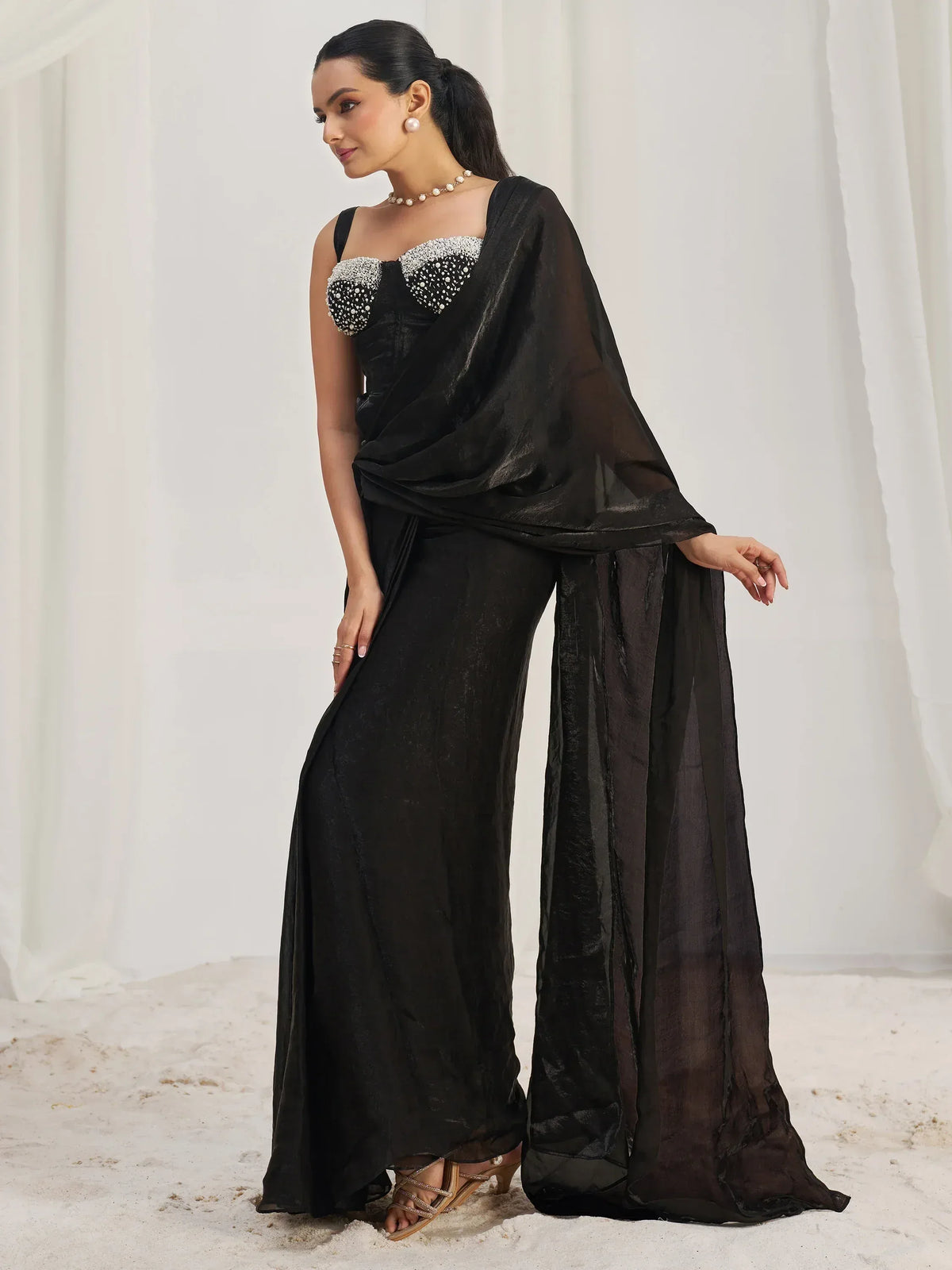 Black ethnic gown with embellished bodice and sheer drape, styled with pearl jewelry