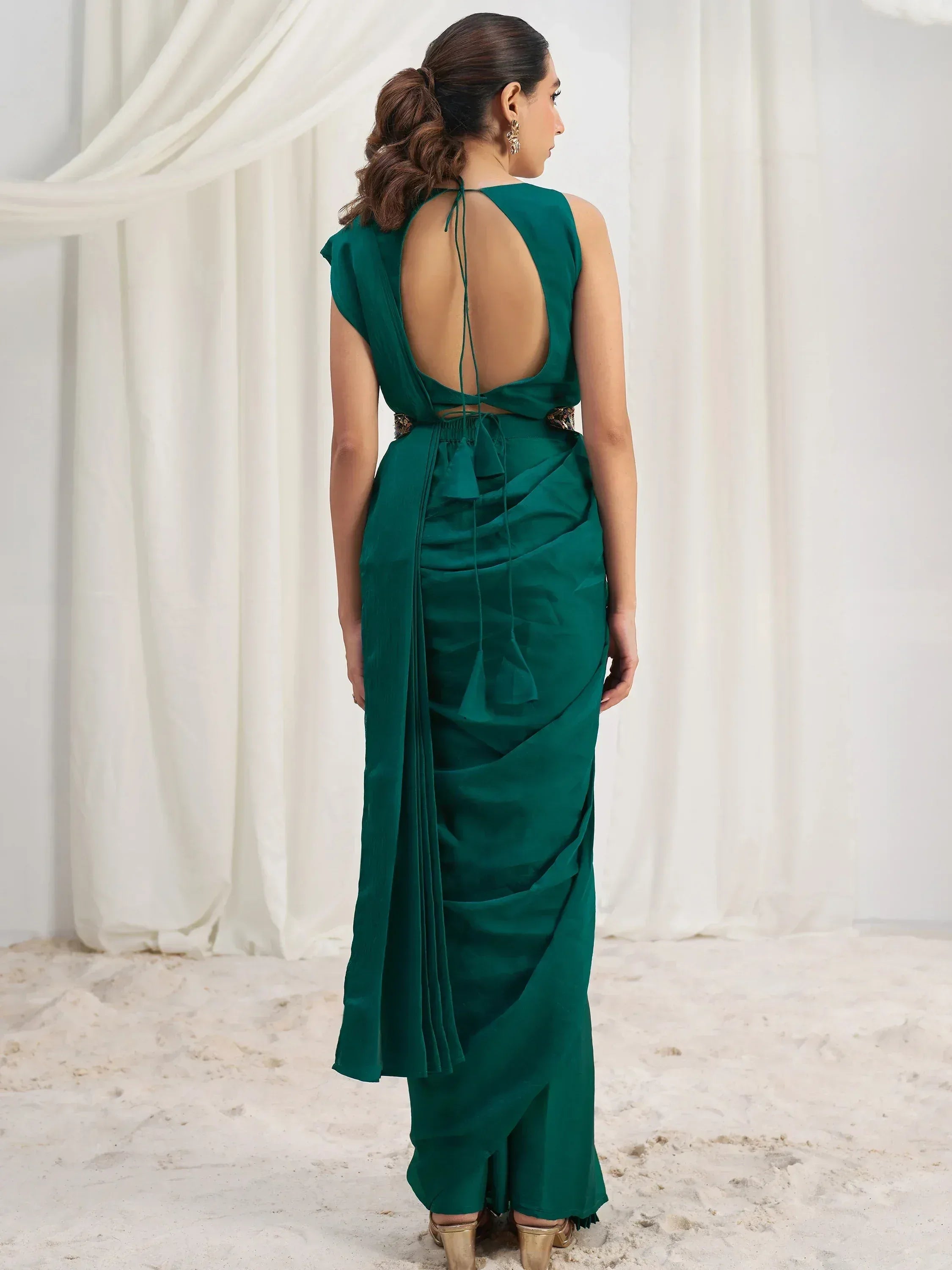 Emerald green ethnic gown with open back and ruched detailing, perfect for Indian occasions