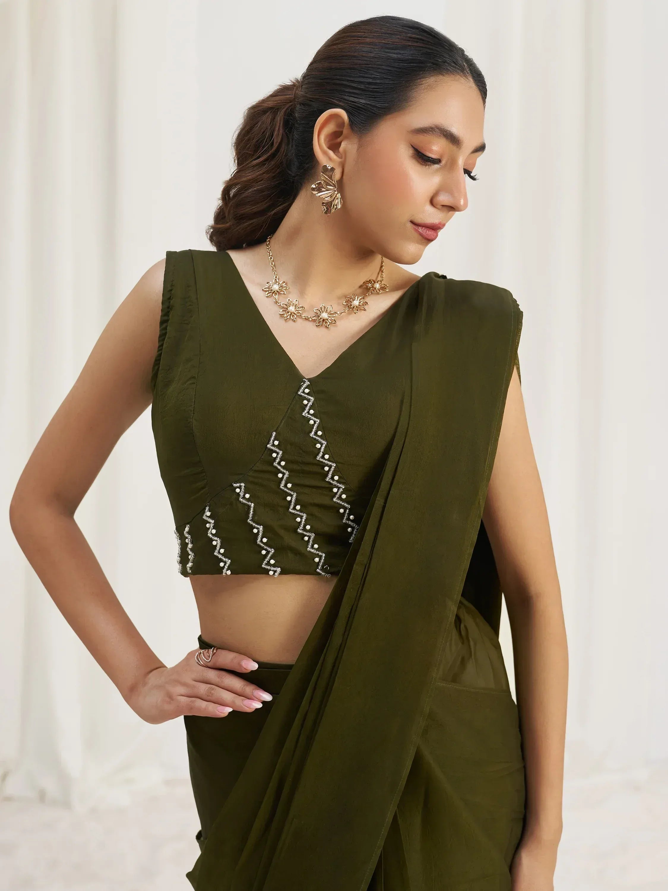 Olive green saree with embroidered blouse, floral jewelry, and elegant styling for ethnic wear.