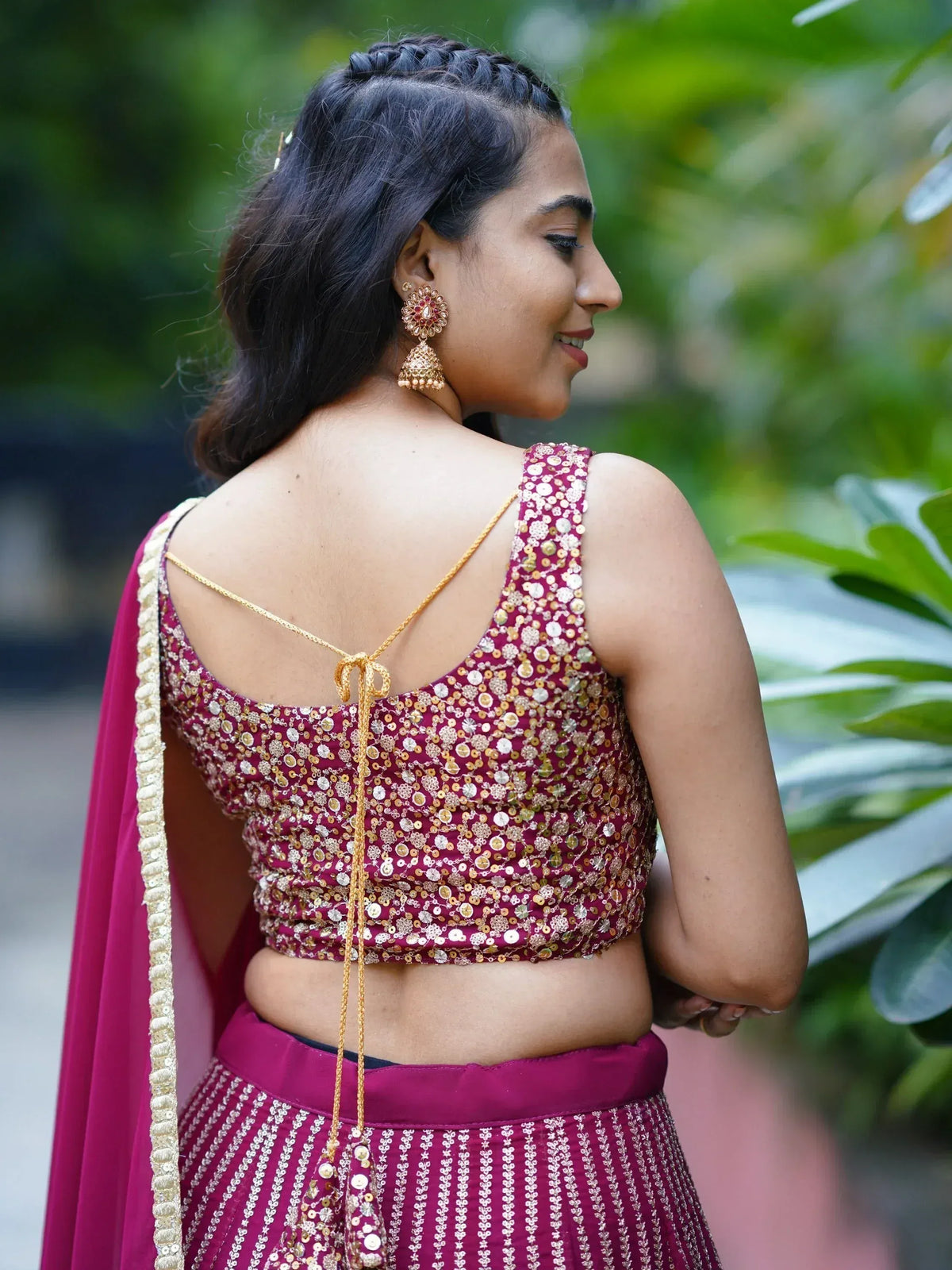 Woman in maroon sequin lehenga choli with gold tie-back, traditional Indian ethnic wear