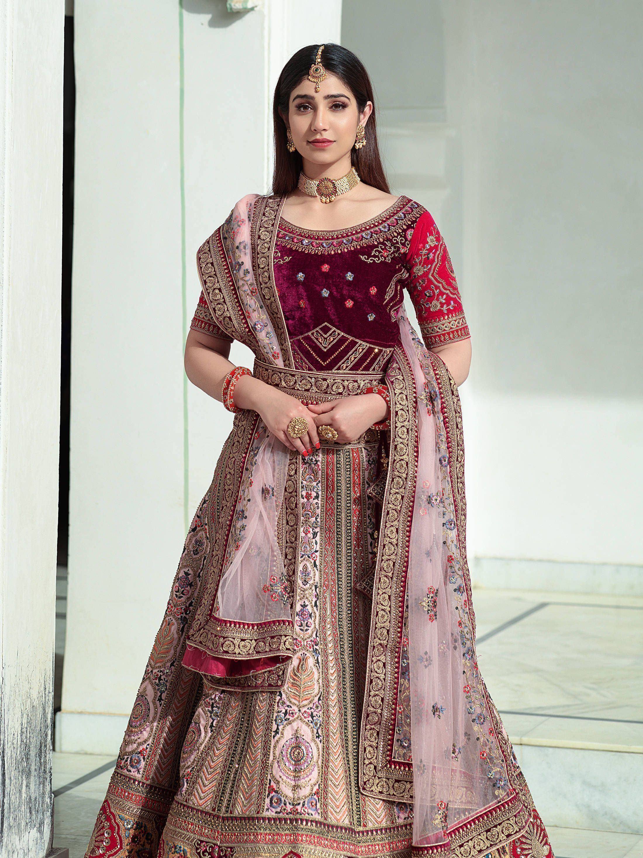 Elegant maroon velvet lehenga choli with intricate gold embroidery and floral dupatta, perfect for Indian weddings.
